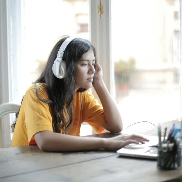 Woman using headphones during an online EMDR therapy session.