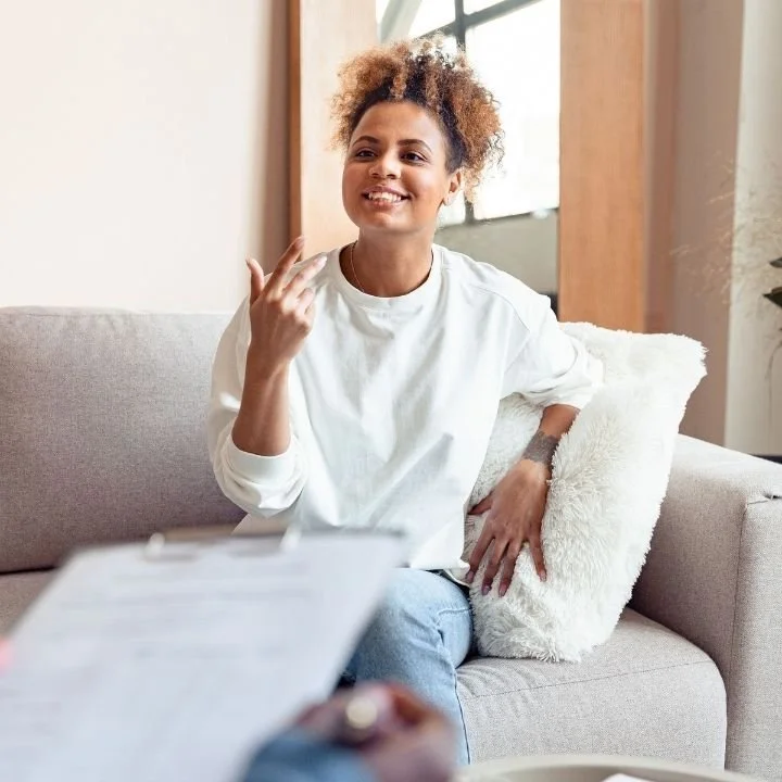 Client smiling during a counseling session while a therapist listens and takes notes.