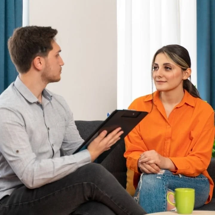 Woman in orange shirt listening calmly to therapist