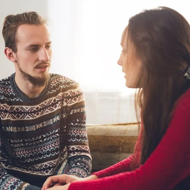 Couple seated facing each other, maintaining eye contact during a calm but serious discussion.