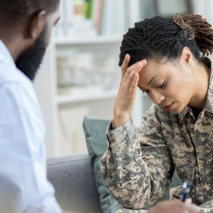 Female veteran in uniform holding forehead during EMDR therapy session