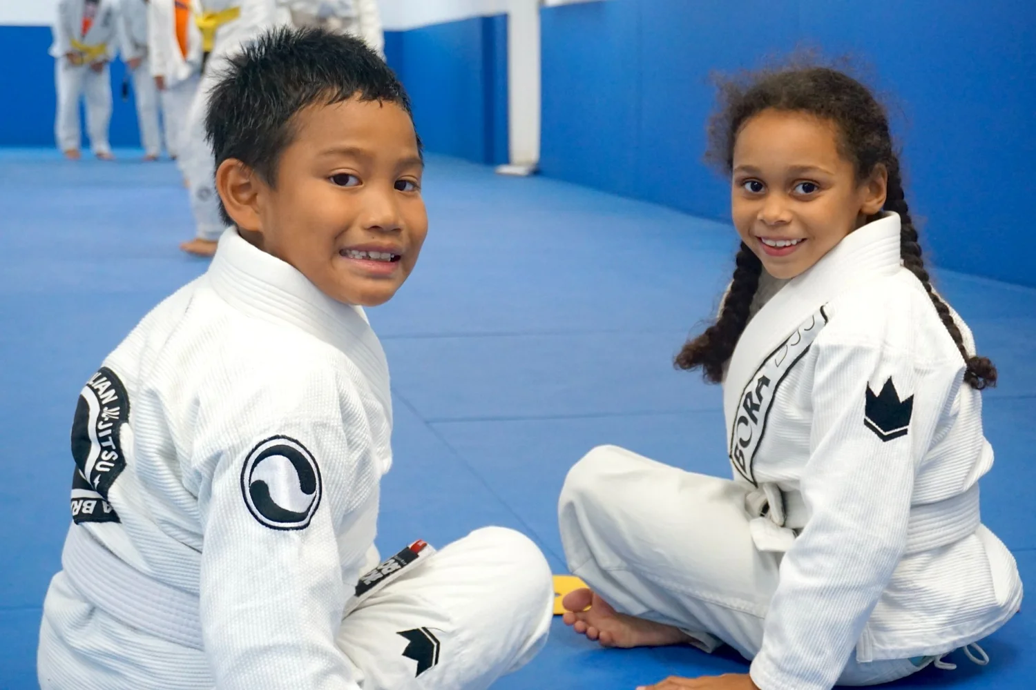 Two children smiling together in their Bora Jiu-Jitsu uniforms