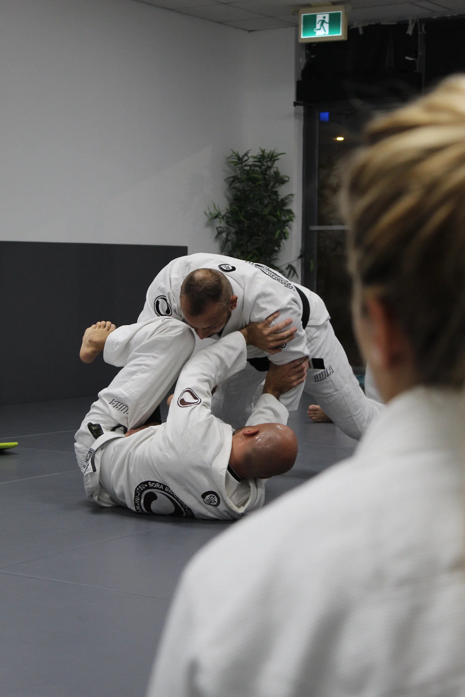 A coach demonstrating a Gi technique while students watch