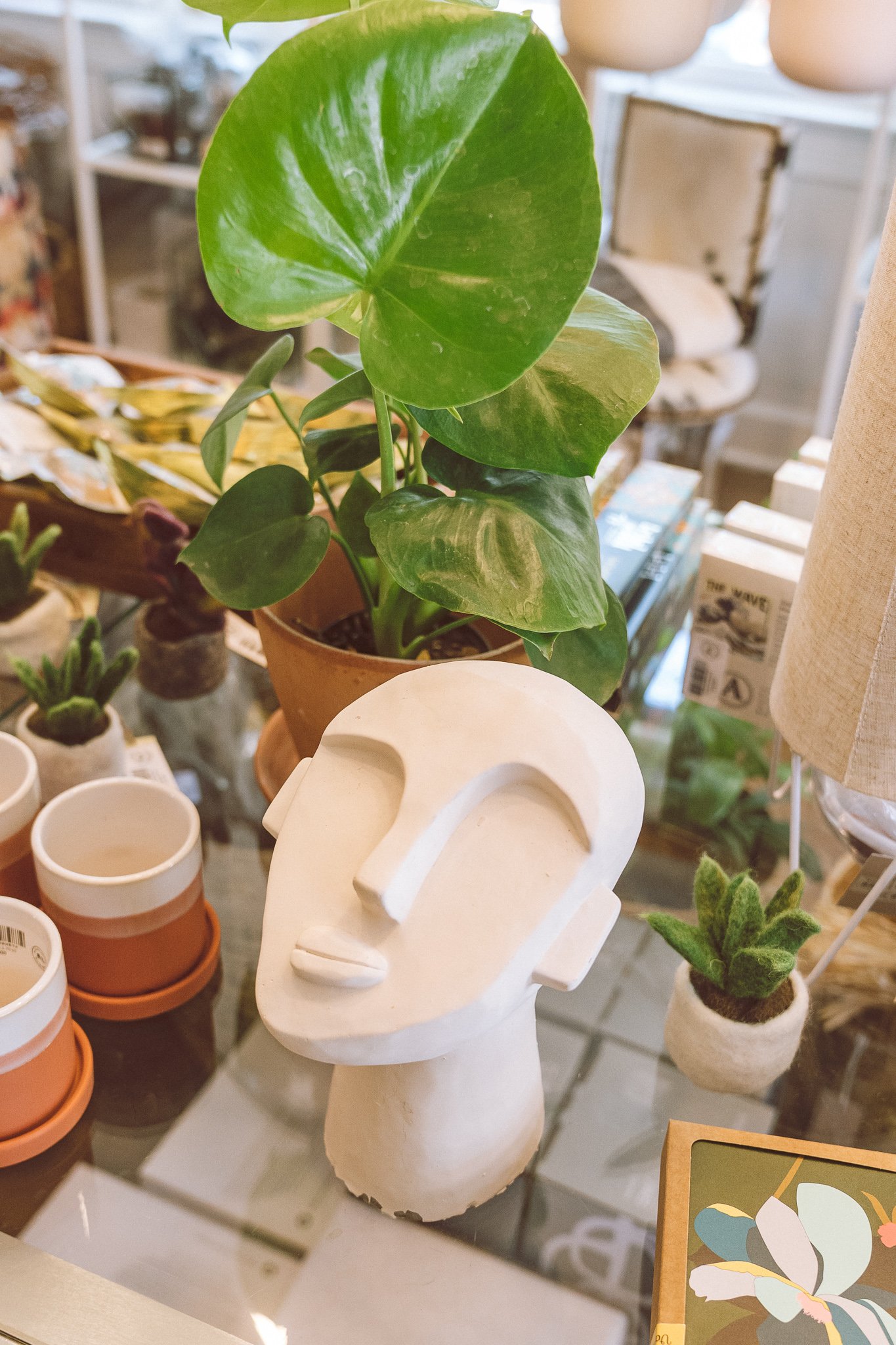 Decorative ceramic head sculpture with potted plant and assorted home decor items on a table.
