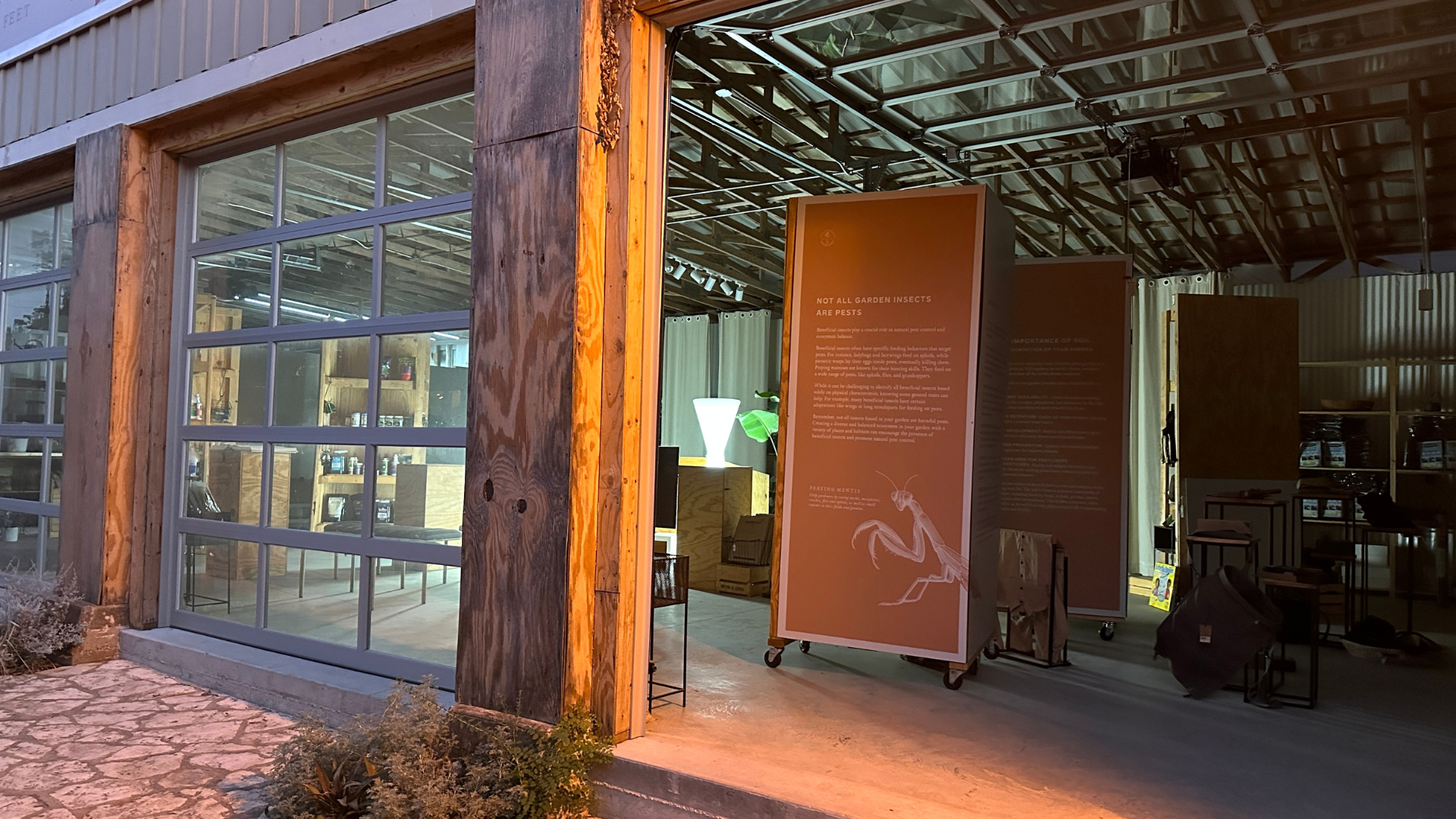 Industrial-style building interior with informational signs and garden equipment visible.