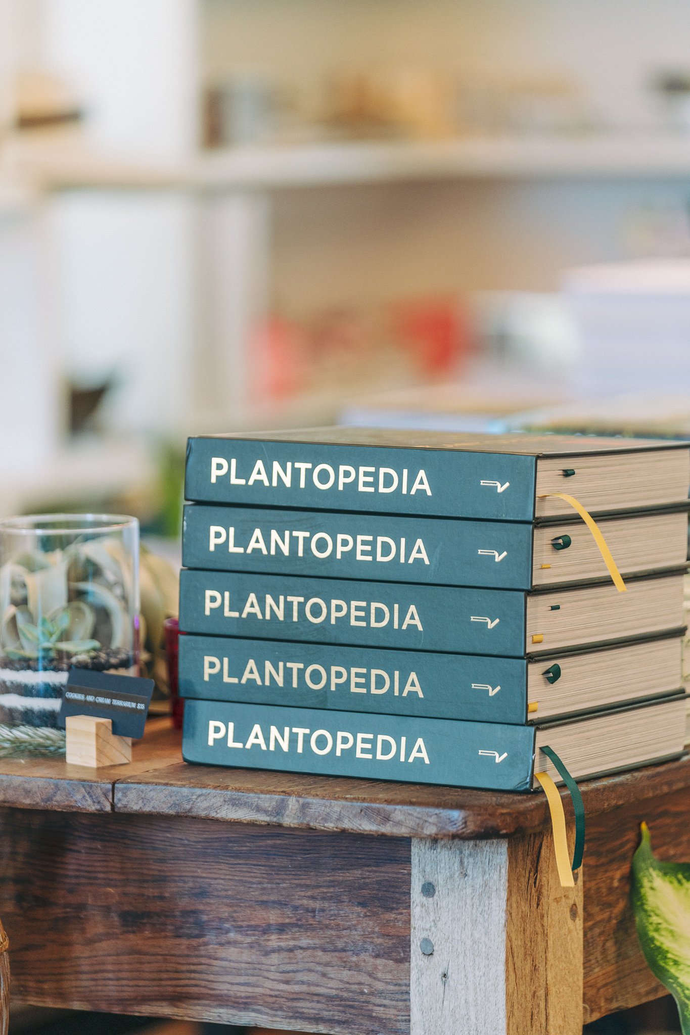 Stack of "Plantopedia" books on wooden table.