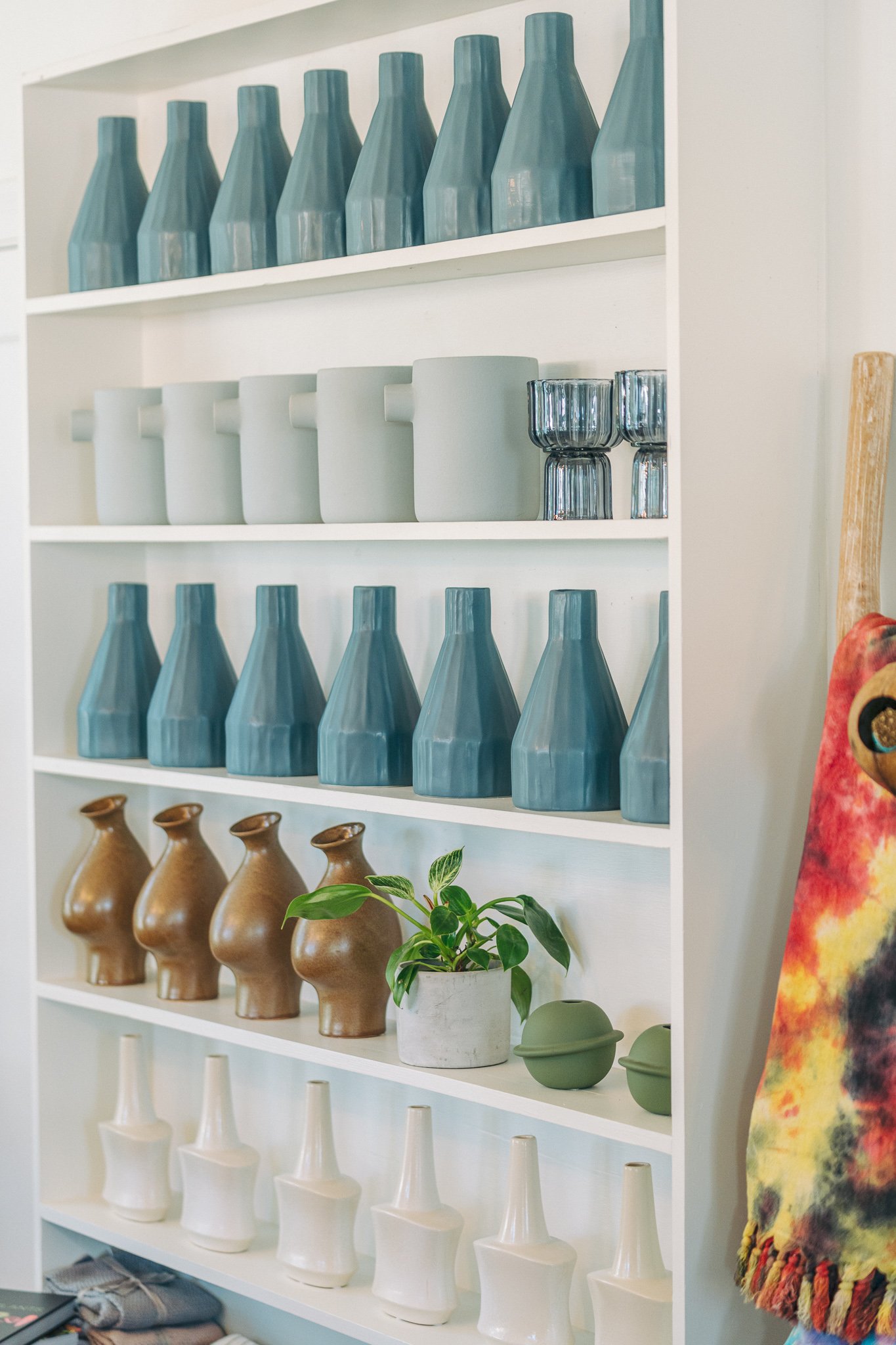 Shelf display with ceramic vases, modern cups, and houseplant