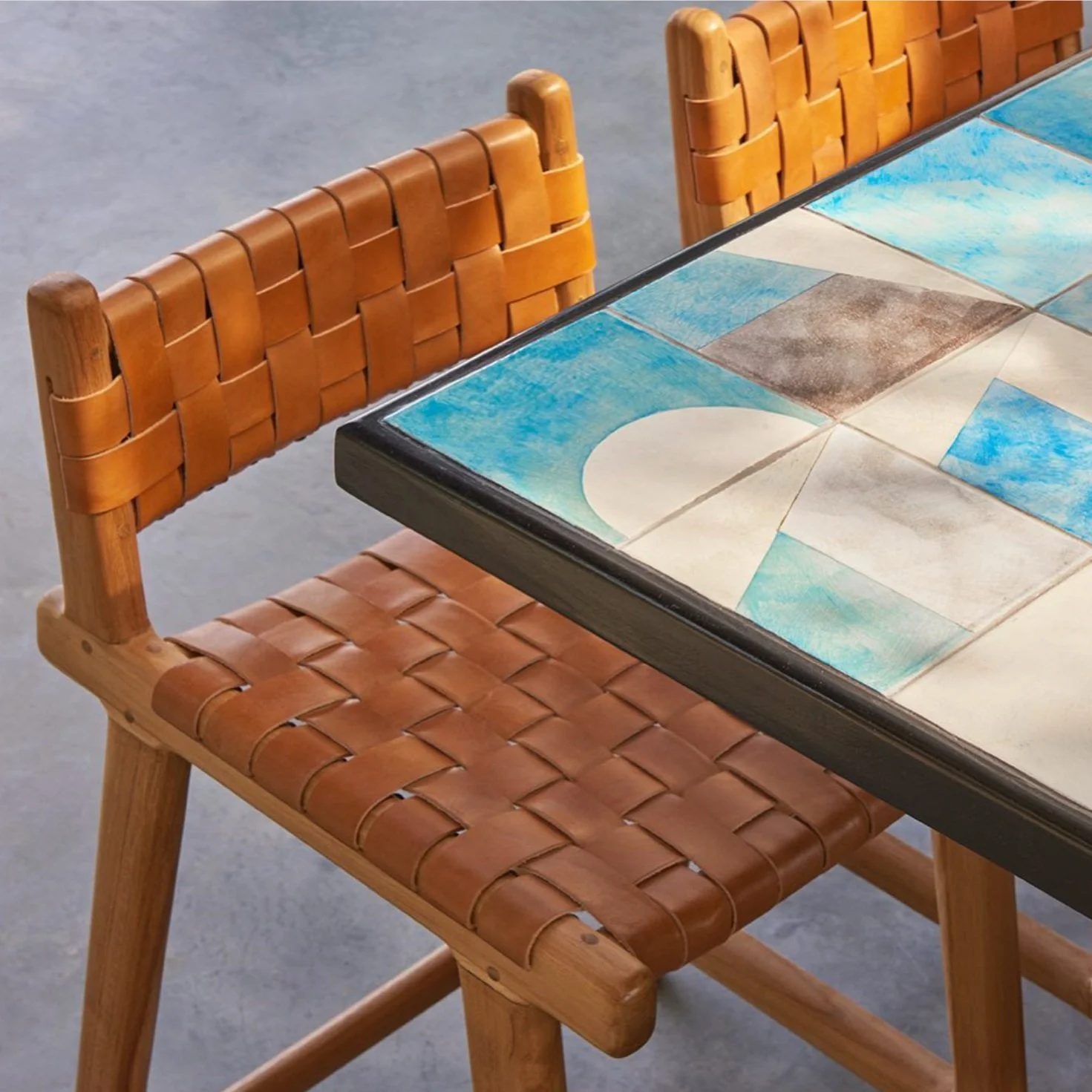 Rockaway Hotel Roof Restaurant. Close-up of a wooden chair with a woven leather seat and backrest, next to a table with a colorful decorated tile top.