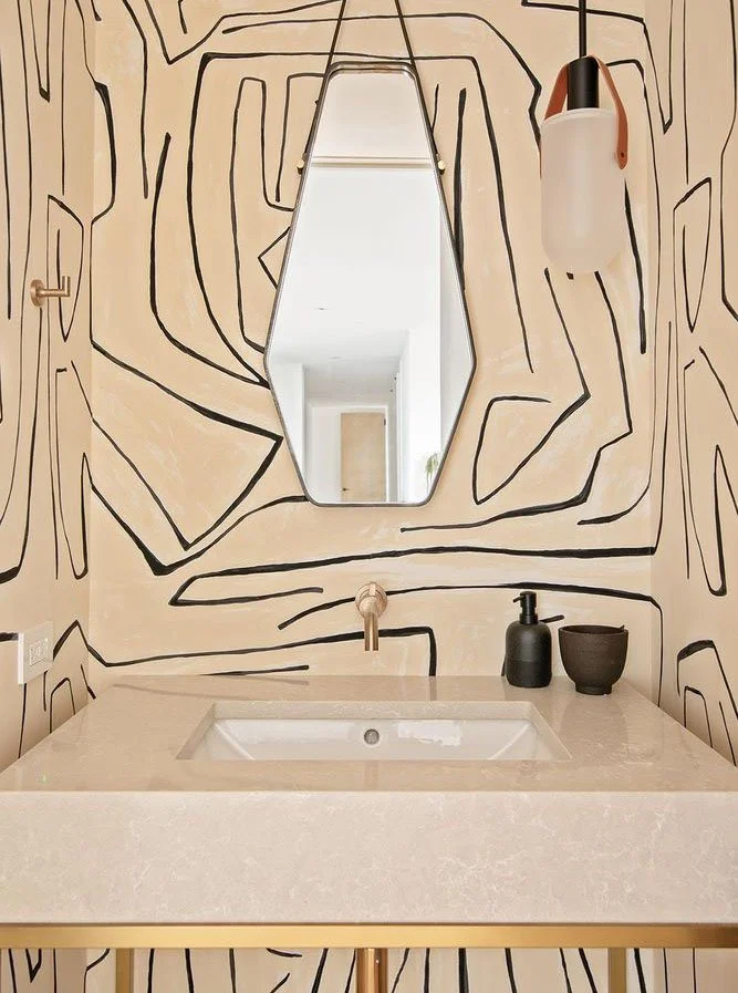 Bathroom sink with wall-mounted mirror and abstract black line art wall design.