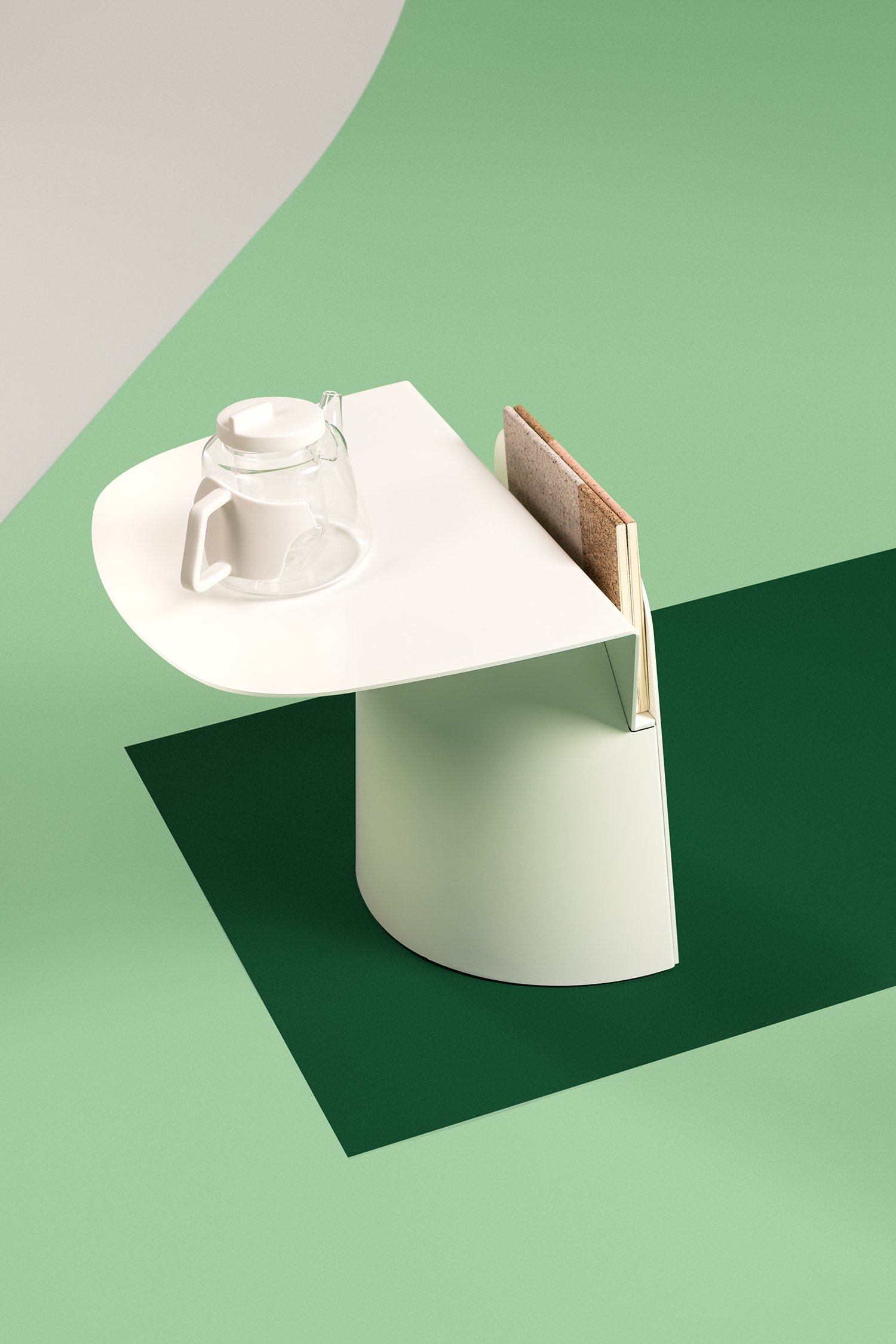Une petite table moderne avec une théière en verre transparent sur le dessus et des livres insérés dans un compartiment sur le côté, sur un fond vert.