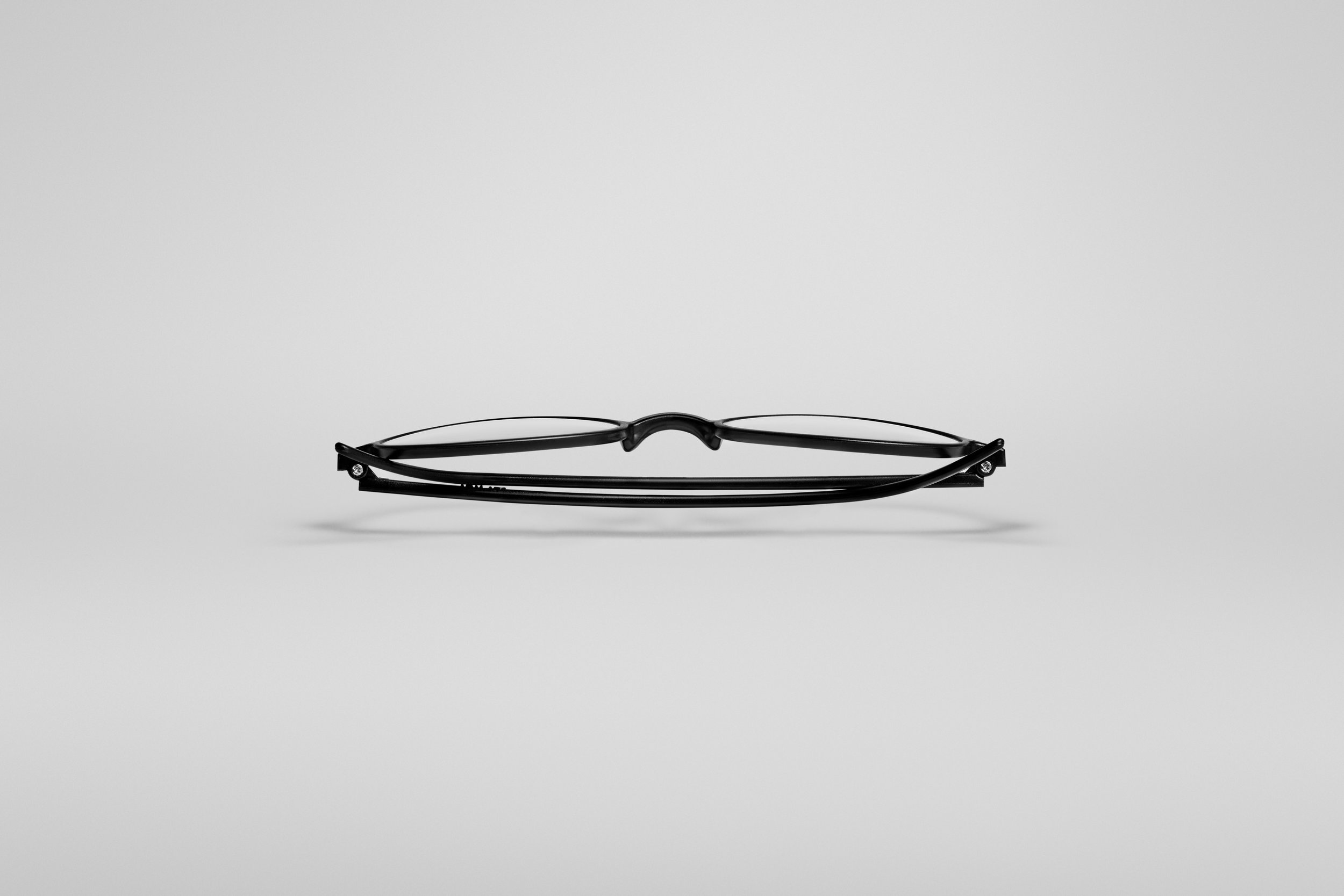Lunettes noires photographiées de côté sur un fond gris clair.