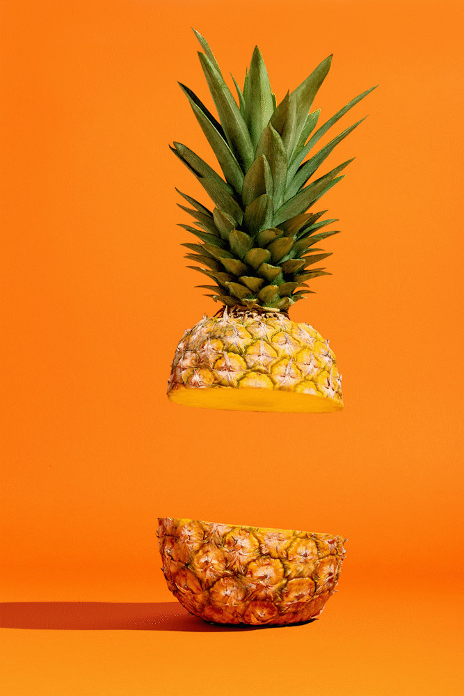 Ananas coupé en deux flottant, fond orange vif.