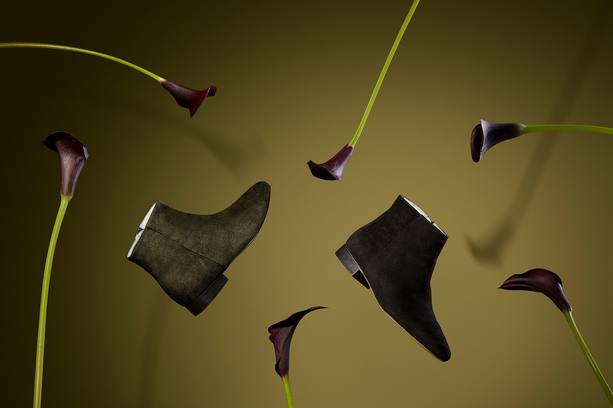 Des bottines en cuir marron foncé entourées de fleurs pourpres sur fond vert.