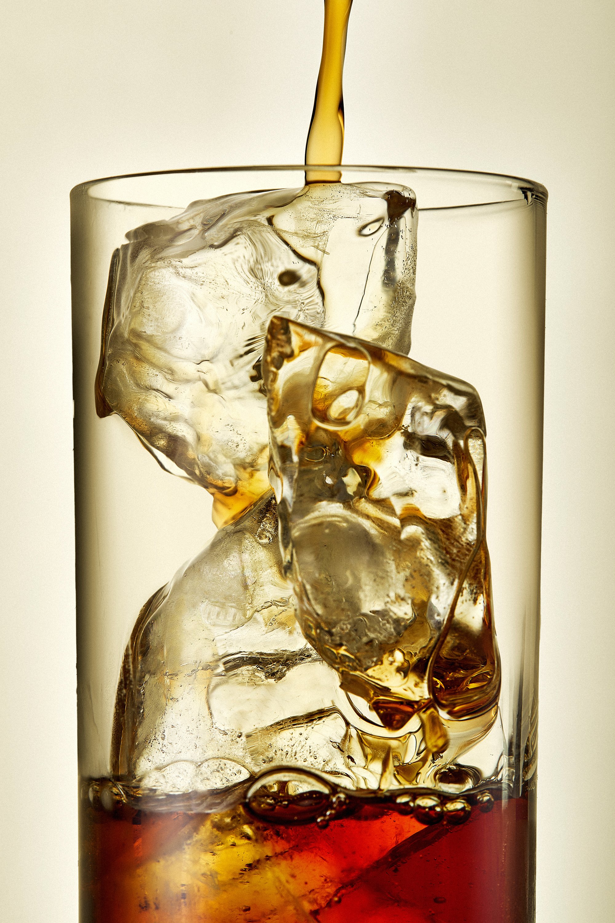 Boisson brune qui coule dans un verre avec des glaçons.