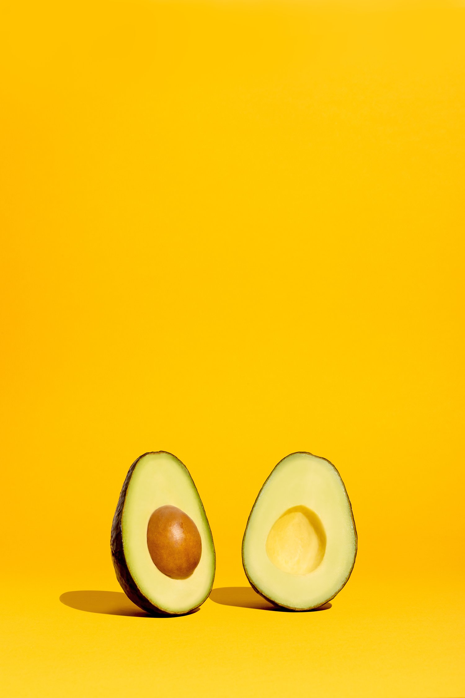 Deux moitiés d'avocat sur fond jaune.