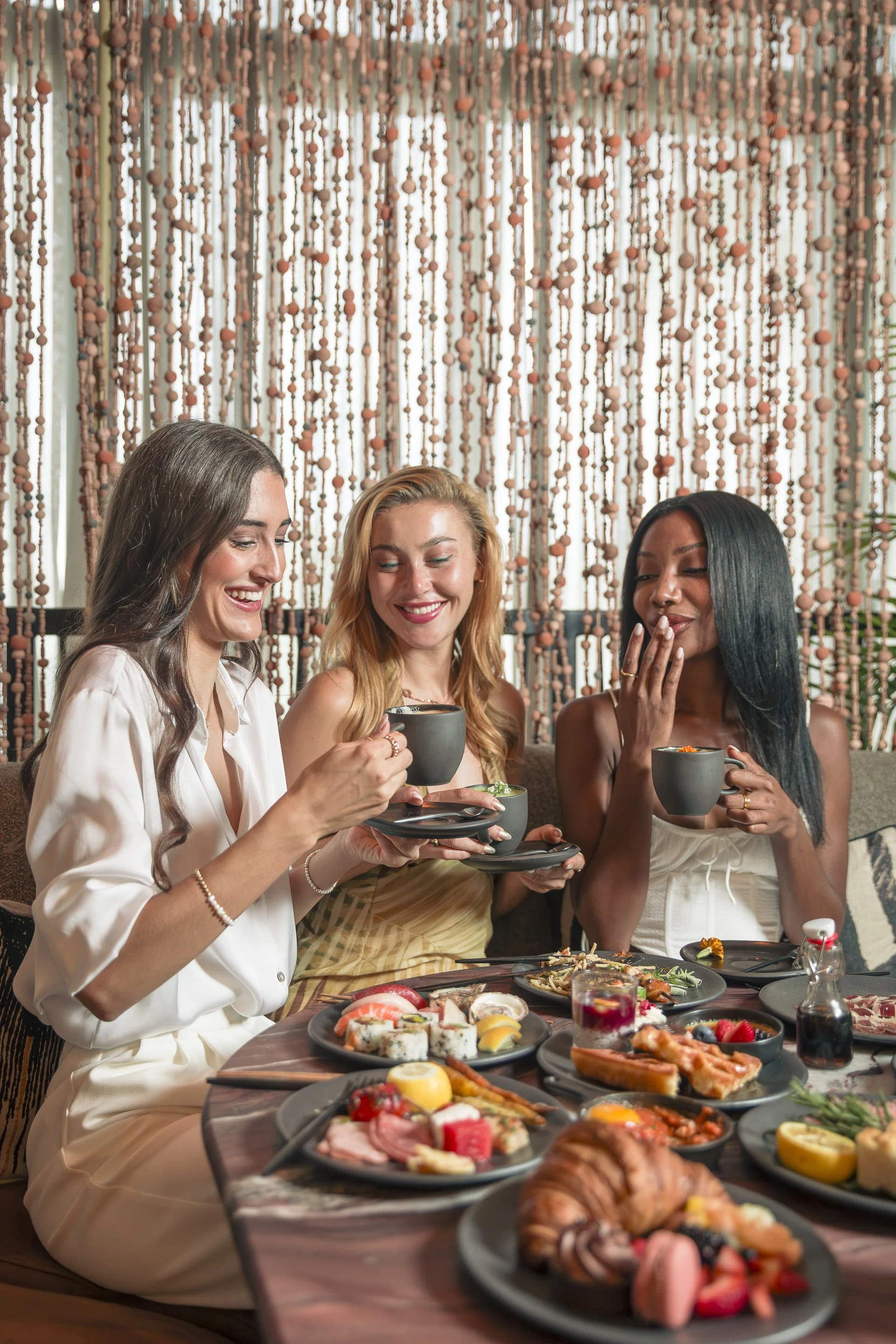 Three elegant woman eating MILA's buffet brunch on the weekend.