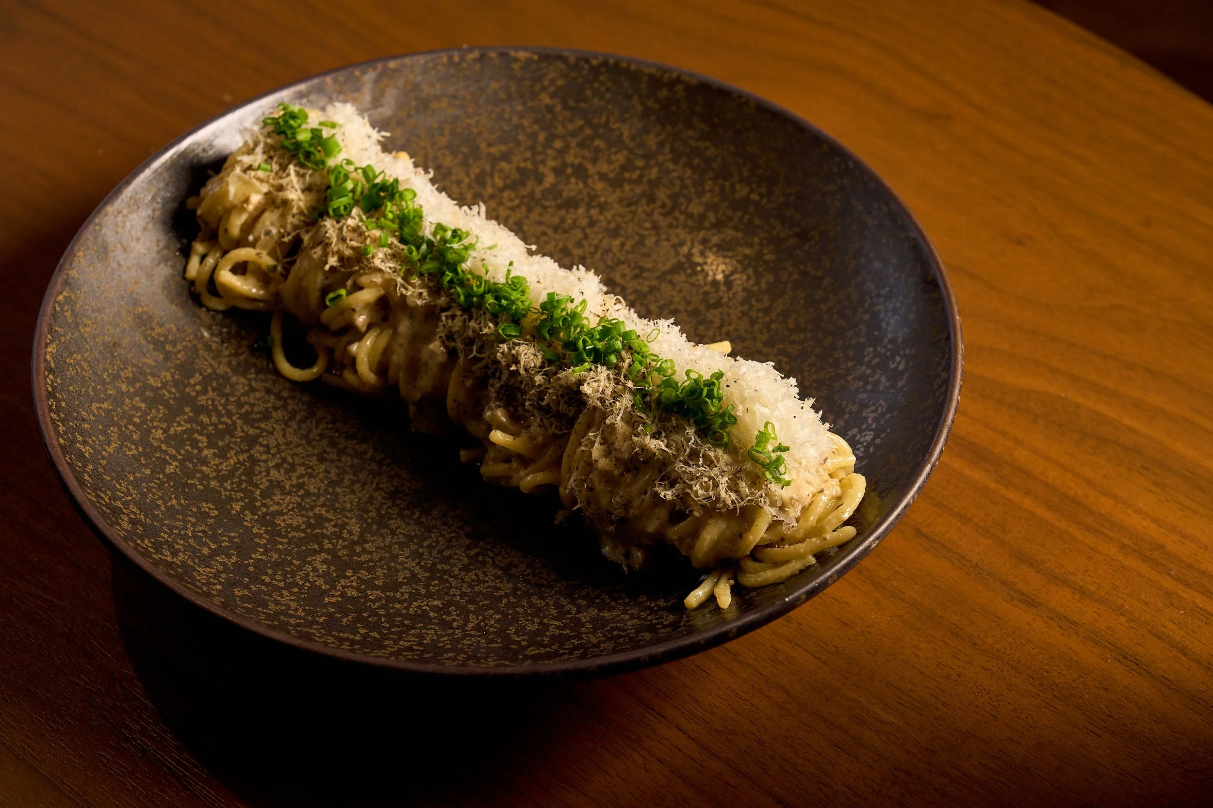 Truffle Pasta garnished elegantly with cheese, and green garnishes.