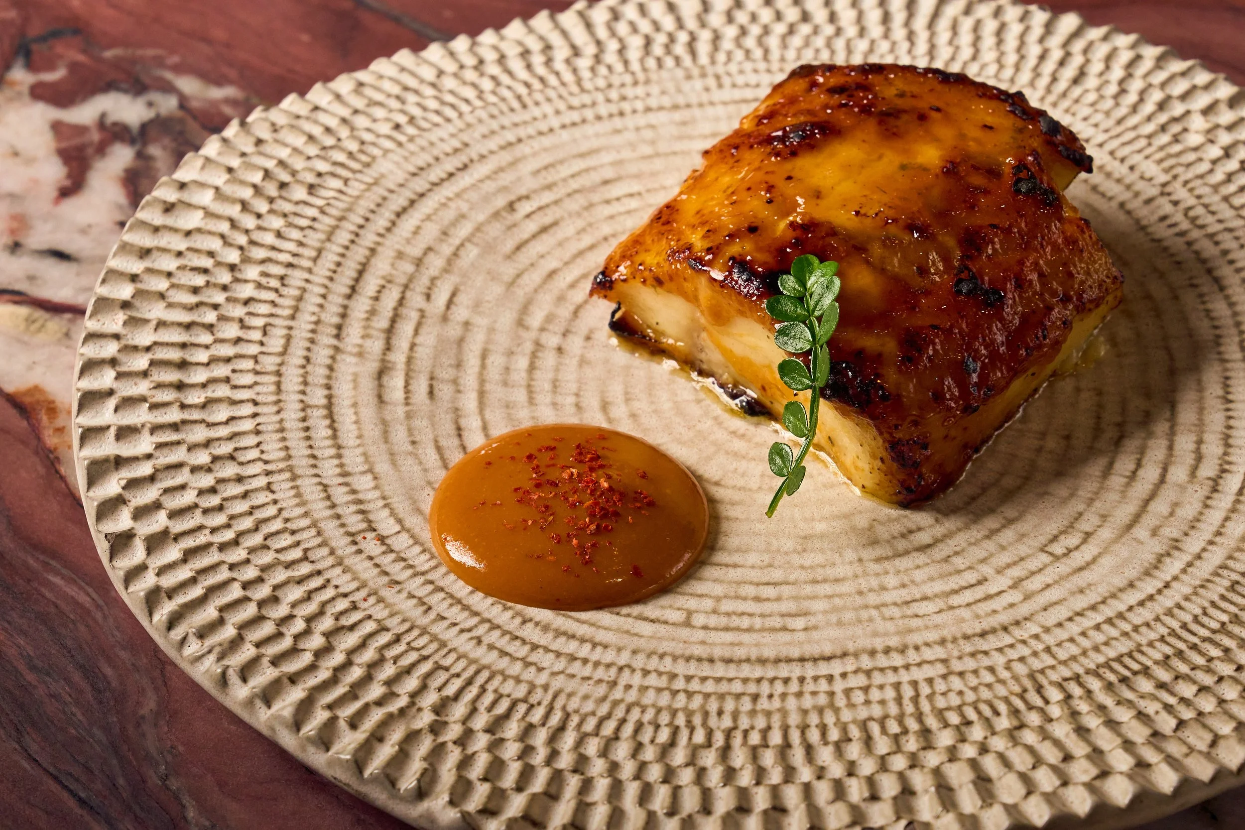 Mediterranean black cod menu item plated beautifully on a textured plate.