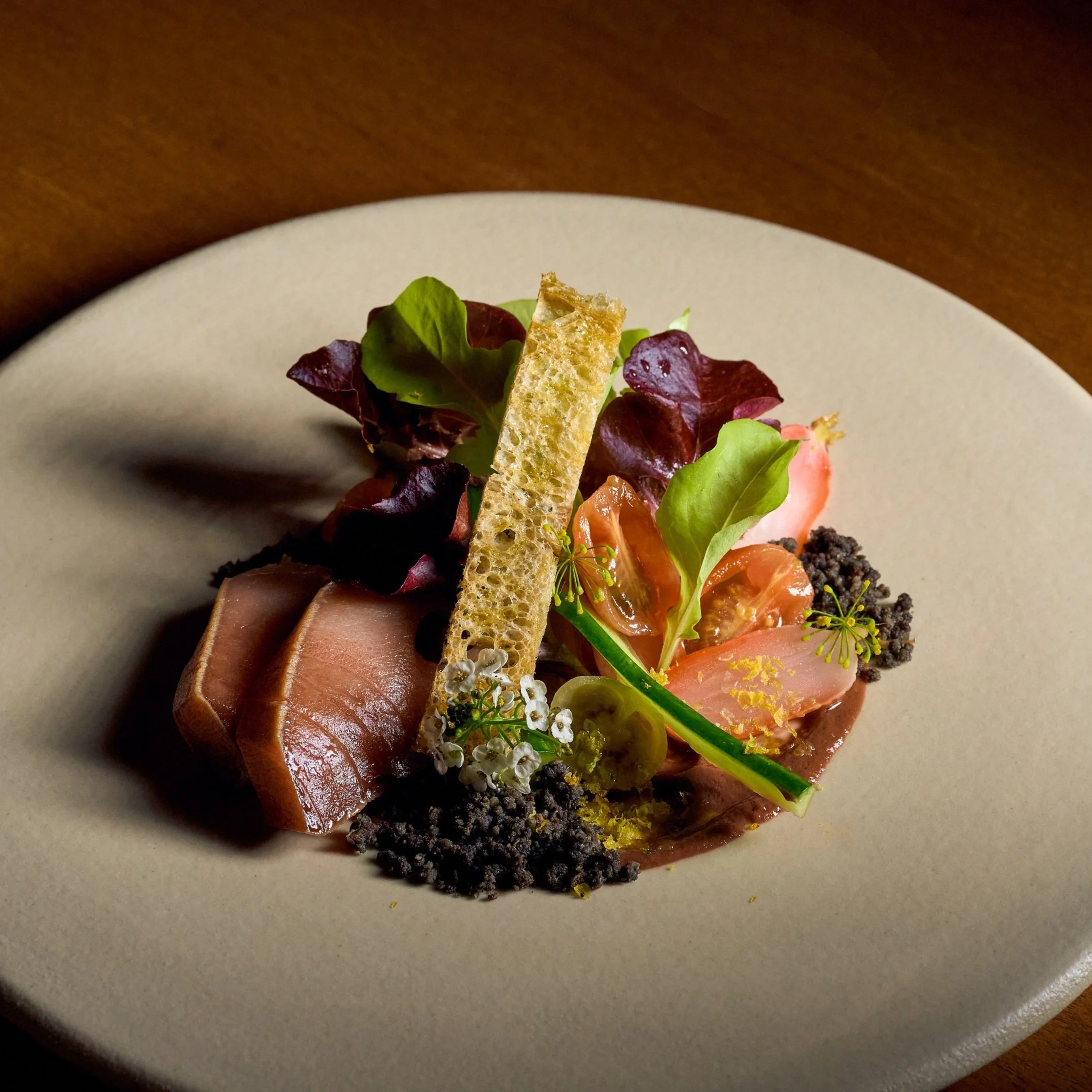 A Tuna Nicois Salad on a cream colored plate with garnishes featured at MILA Omakase.