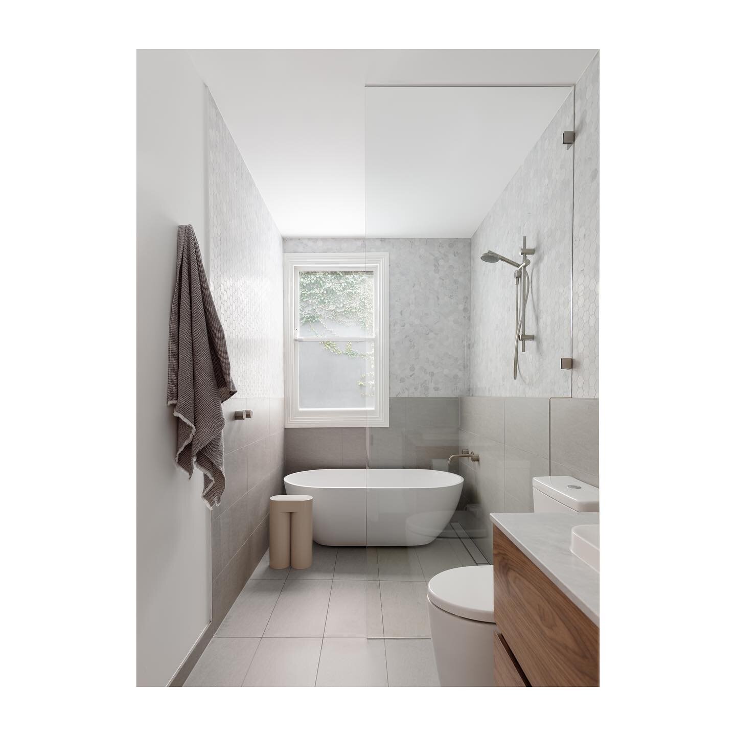 The small footprint of the bathroom meant the bathtub and shower would form a unified wet room to allow for the vanity and toilet to remain within the same space. The laundry was separated from the bathroom by cleverly creating a nook within the hall