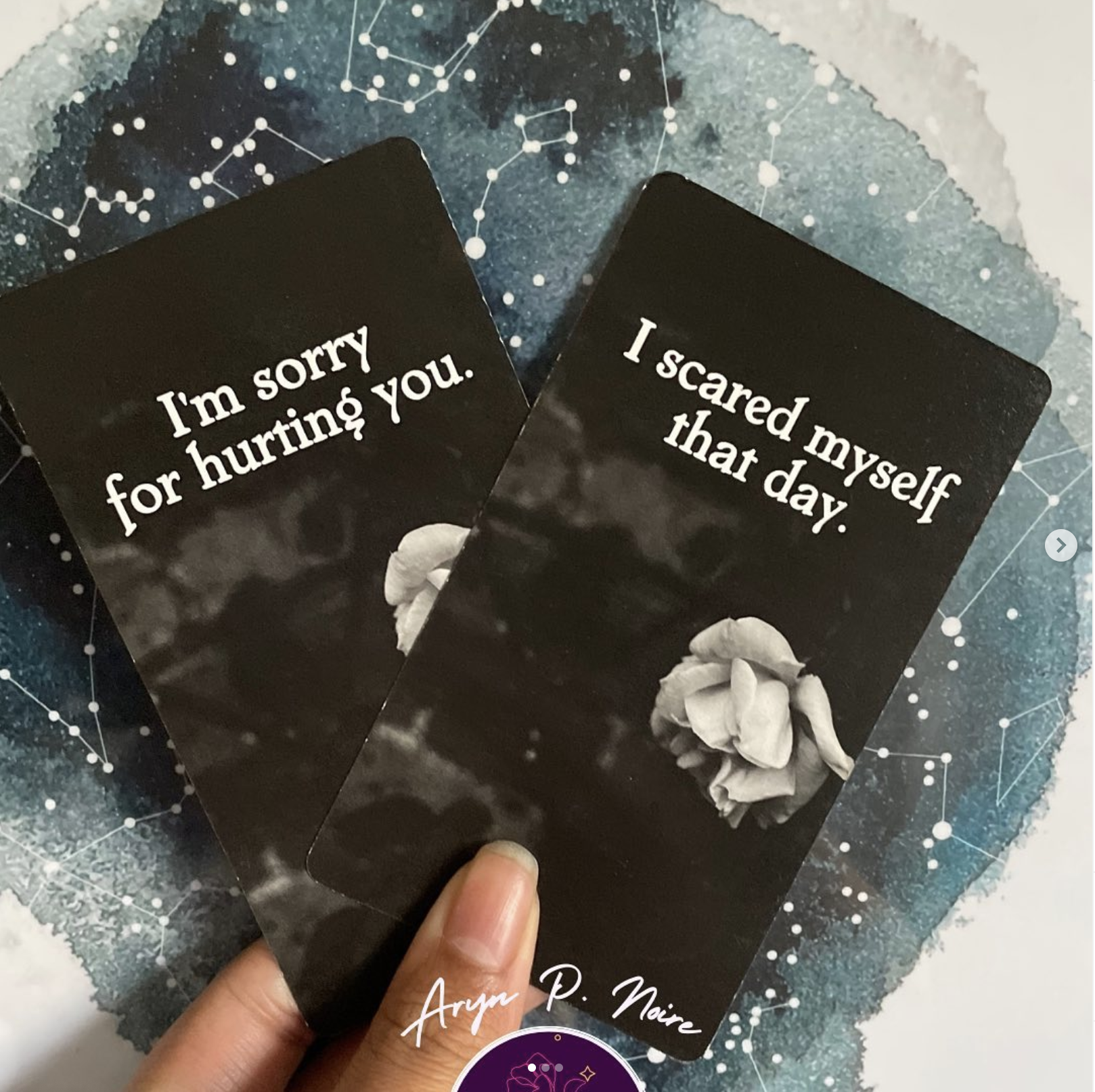 Two tarot cards held against a starry background with Aryn P. Noire logo.