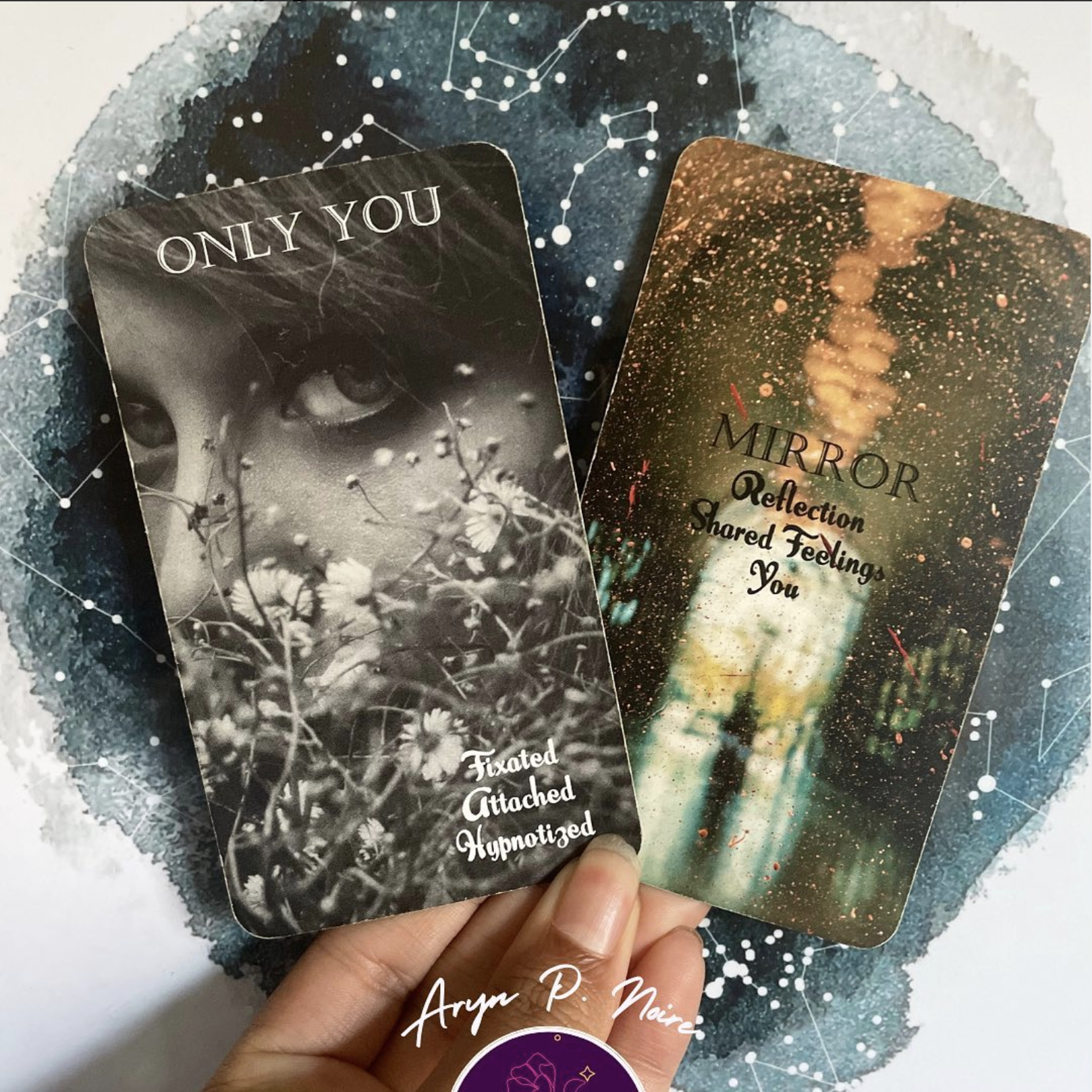 Two tarot cards held against a starry background with Aryn P. Noire logo.