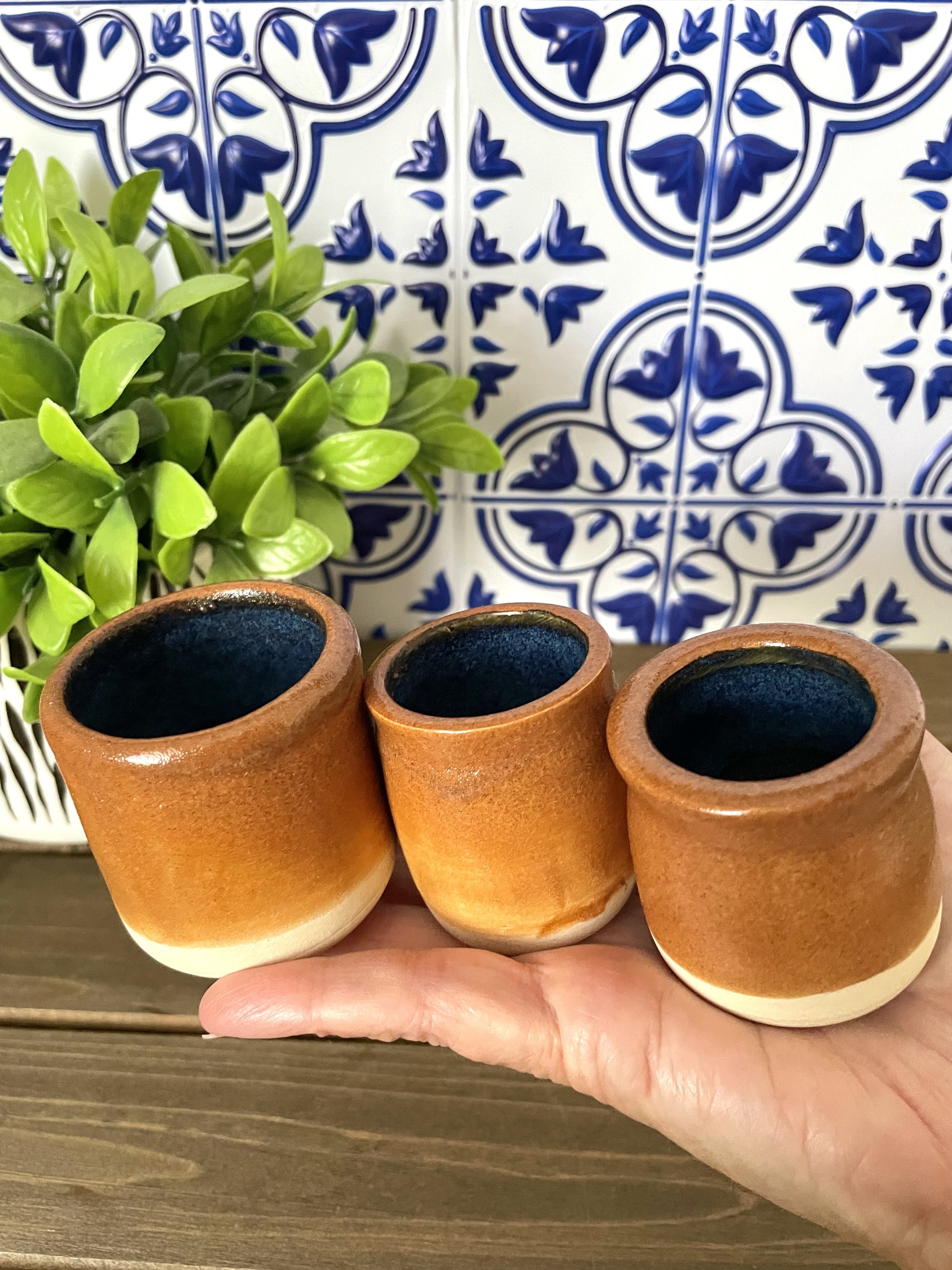 Rustic ceramic shot glasses. Stoneware with floating blue on inside and Shino (brown toast) glaze on the outside with trimmed bottom. Nontoxic and food safe glazes. Approximately 1 oz.