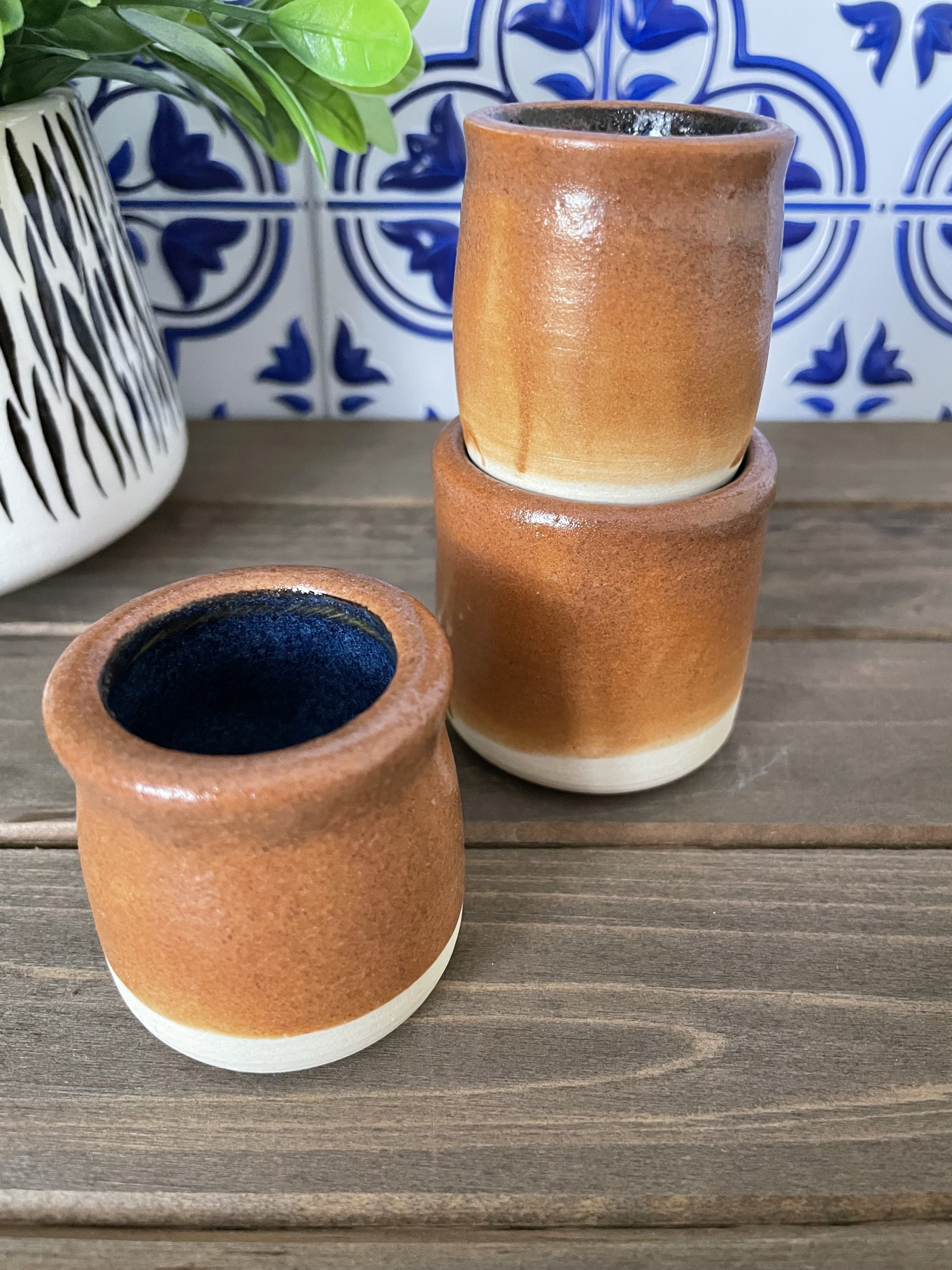 Rustic ceramic shot glasses. Stoneware with floating blue on inside and Shino (brown toast) glaze on the outside with trimmed bottom. Nontoxic and food safe glazes. Approximately 1 oz.