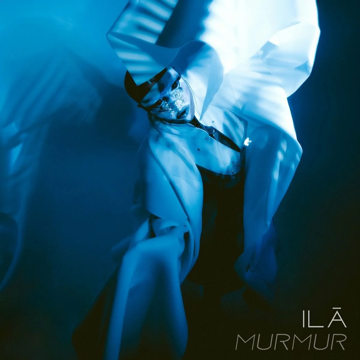 Abstract portrait of a person with painted face and flowing fabric, in blue tones, with the text "ILÃ MURMUR." TRANS VOICES was part of the EP as an artist collaborator.