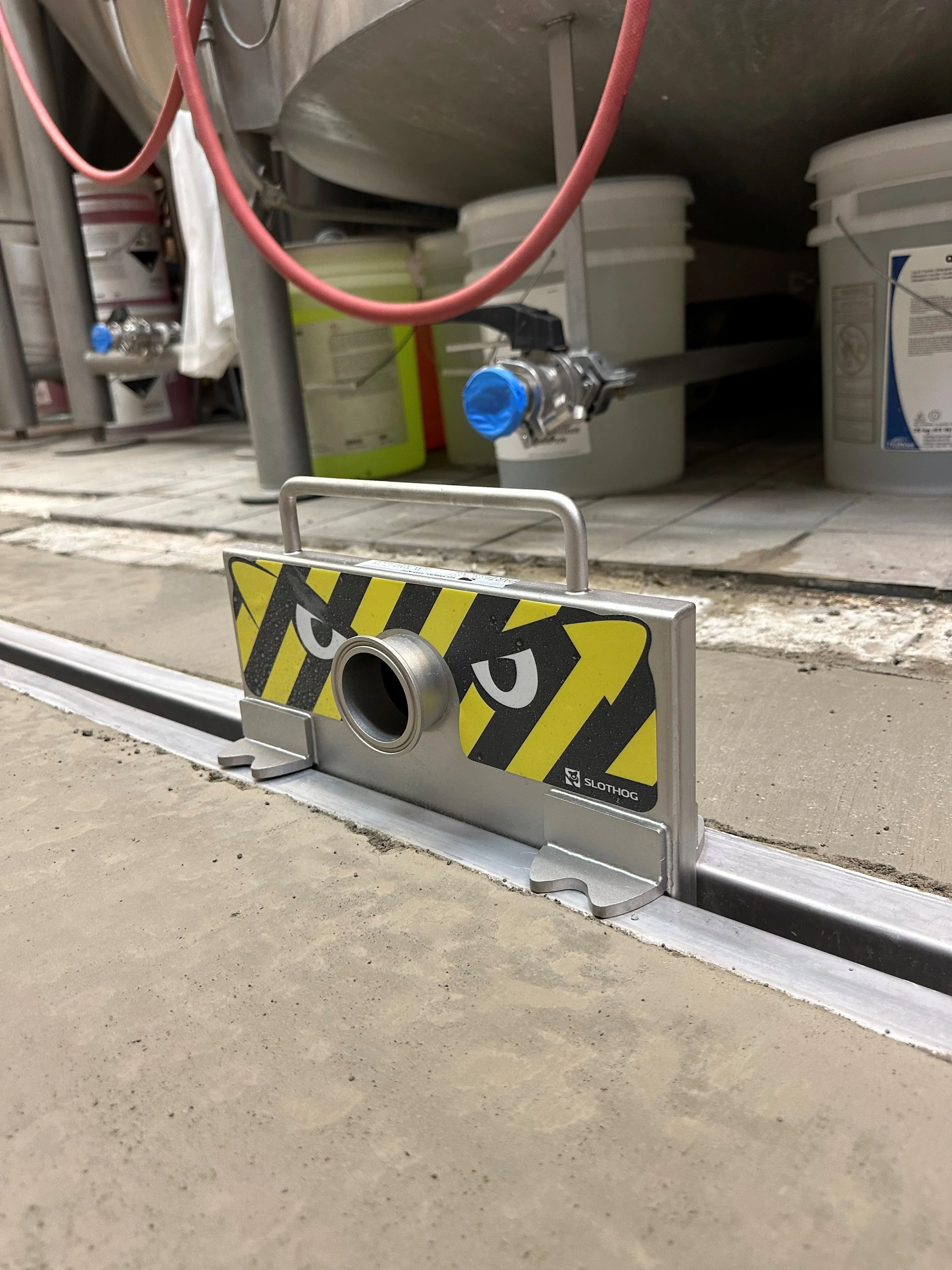 Water pipe in a laboratory or industrial setting, with buckets and equipment in the background.