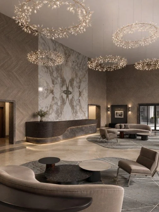 Luxurious hotel lobby with modern seating, marble accents, and ornate circular chandeliers.