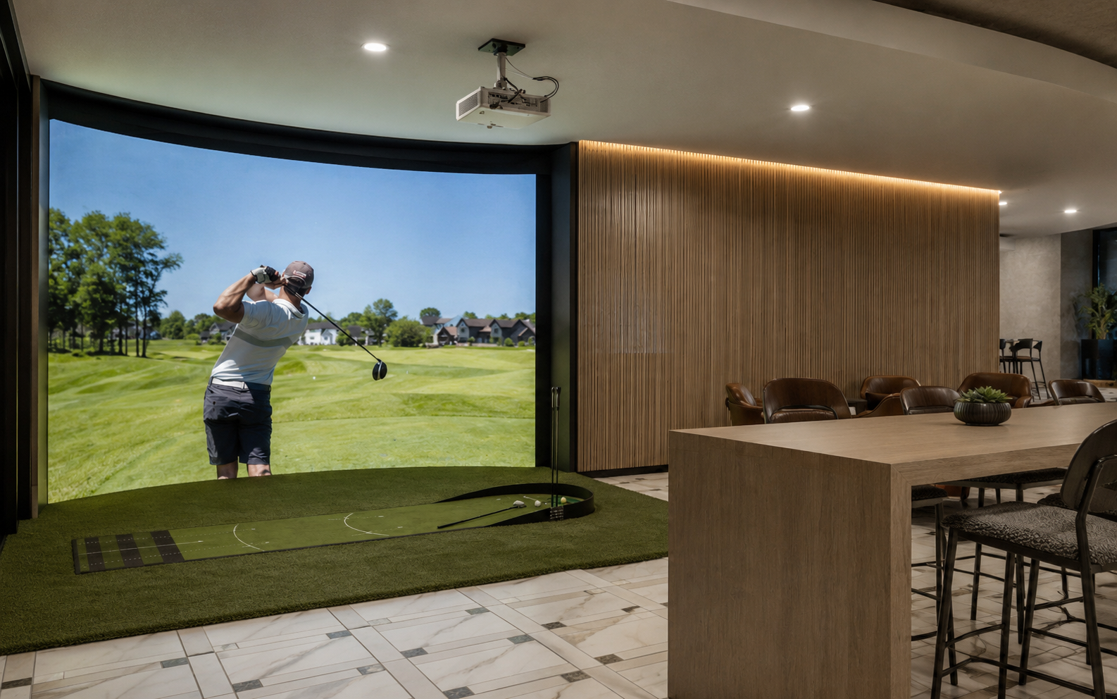Indoor golf simulation room with a large screen showing a golfer on a golf course, a golf mat, and seating area.