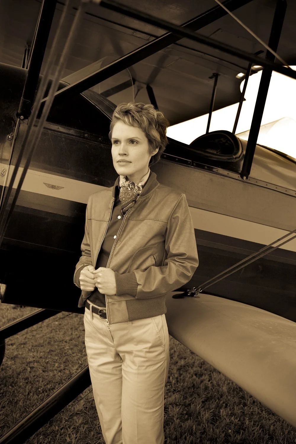 Performer portraying Amelia Earhart beside a vintage airplane