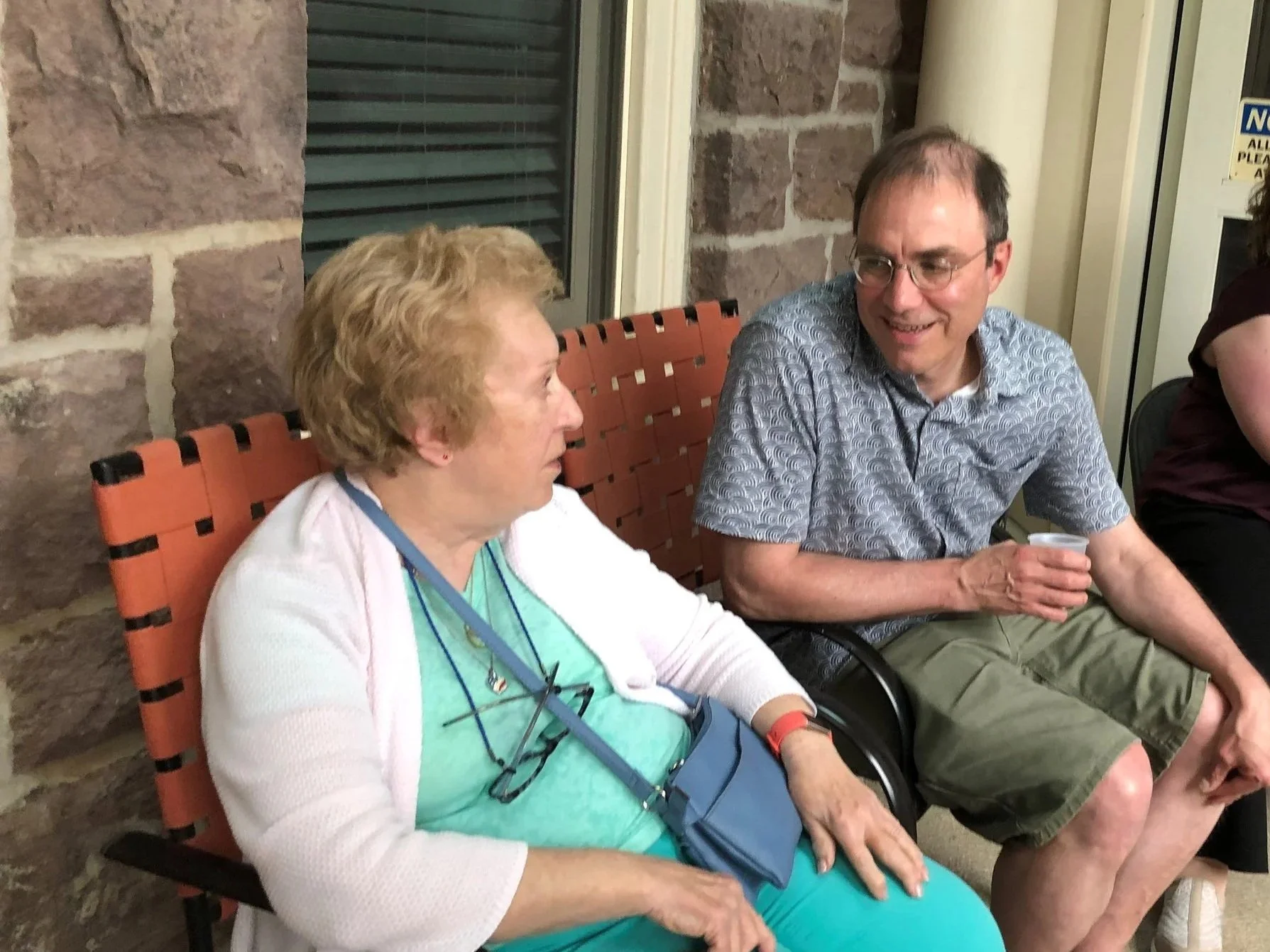 Two attendees seated and talking on the porch during Newtown Porchfest at Friends Village