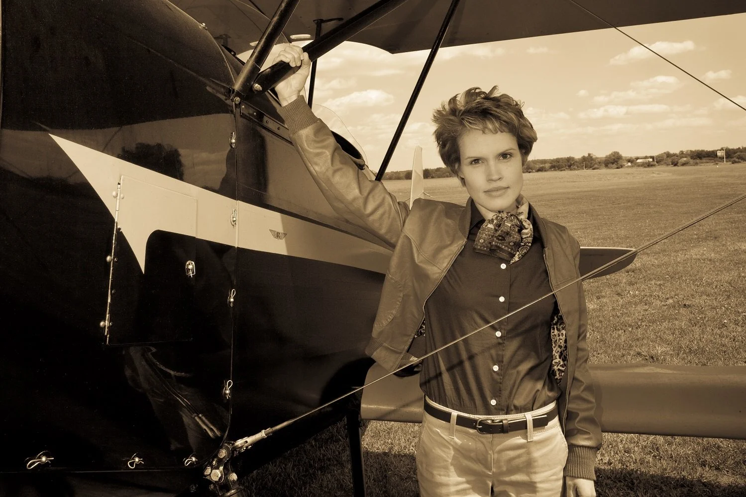 Performer portraying Amelia Earhart standing beside a vintage airplane