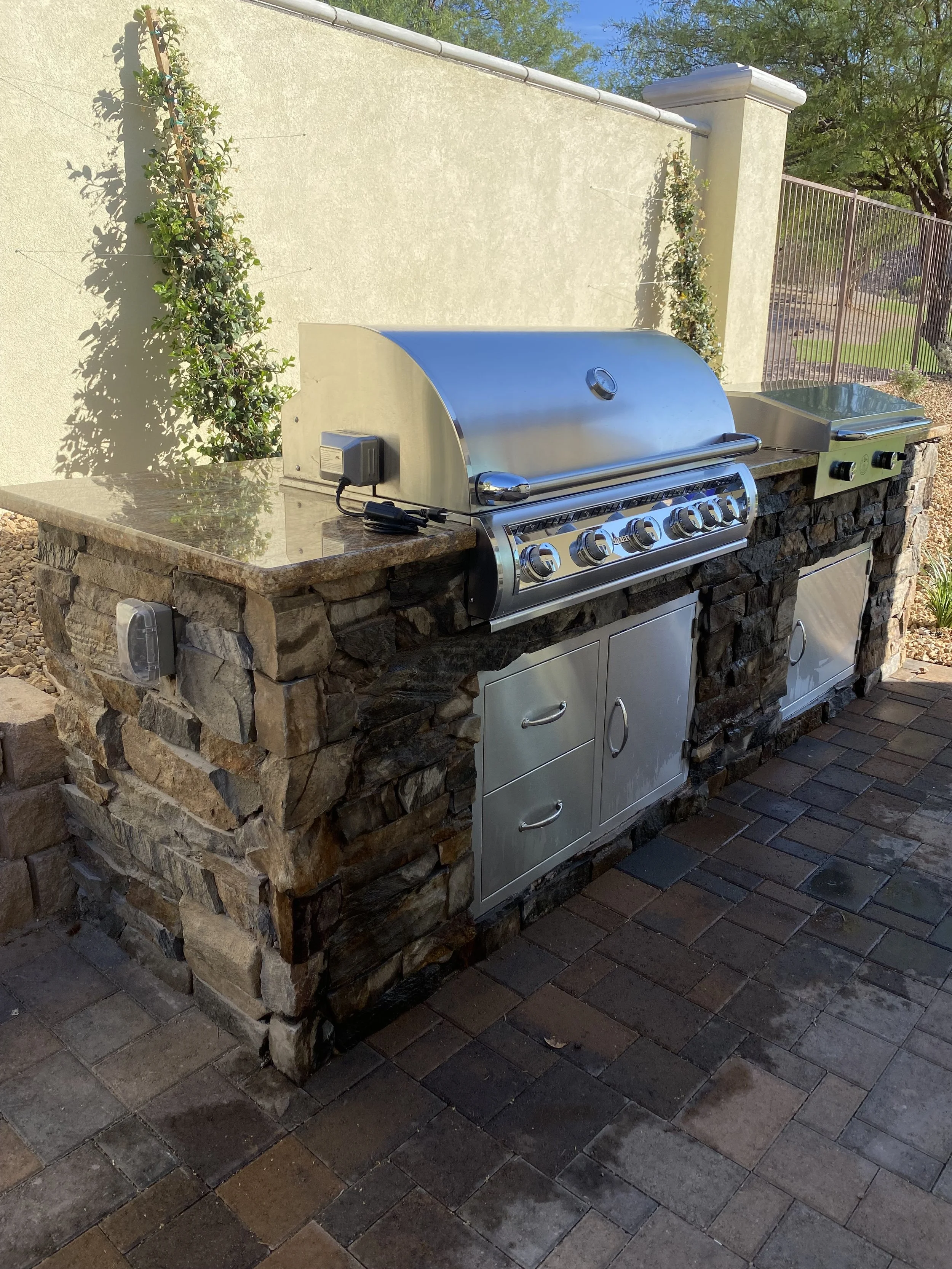Outdoor kitchen with stone and stainless steel grill on a patio