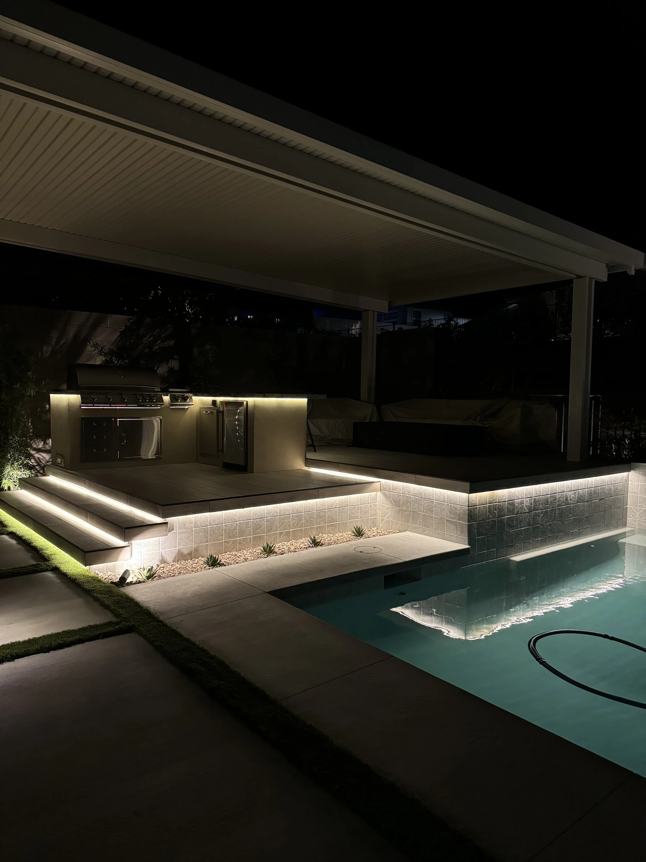 Backyard patio with a swimming pool and illuminated steps at night