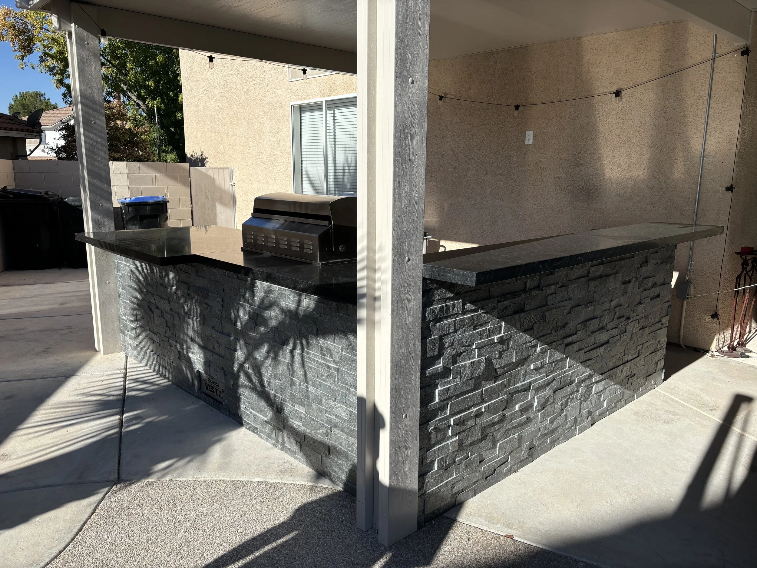 Outdoor kitchen area with a stone countertop and built-in grill.