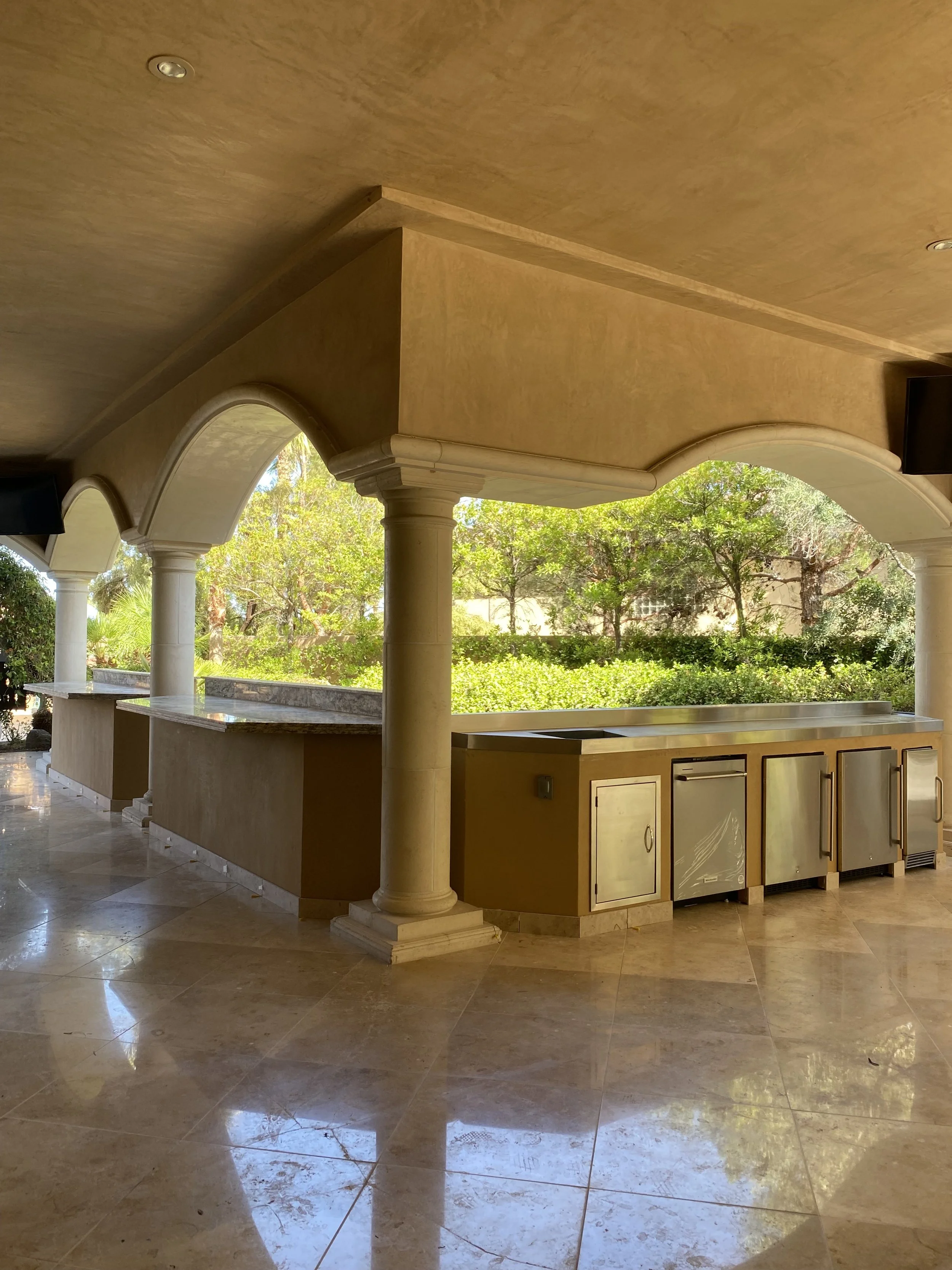 Outdoor patio with stone columns and built-in stainless steel kitchen appliances.