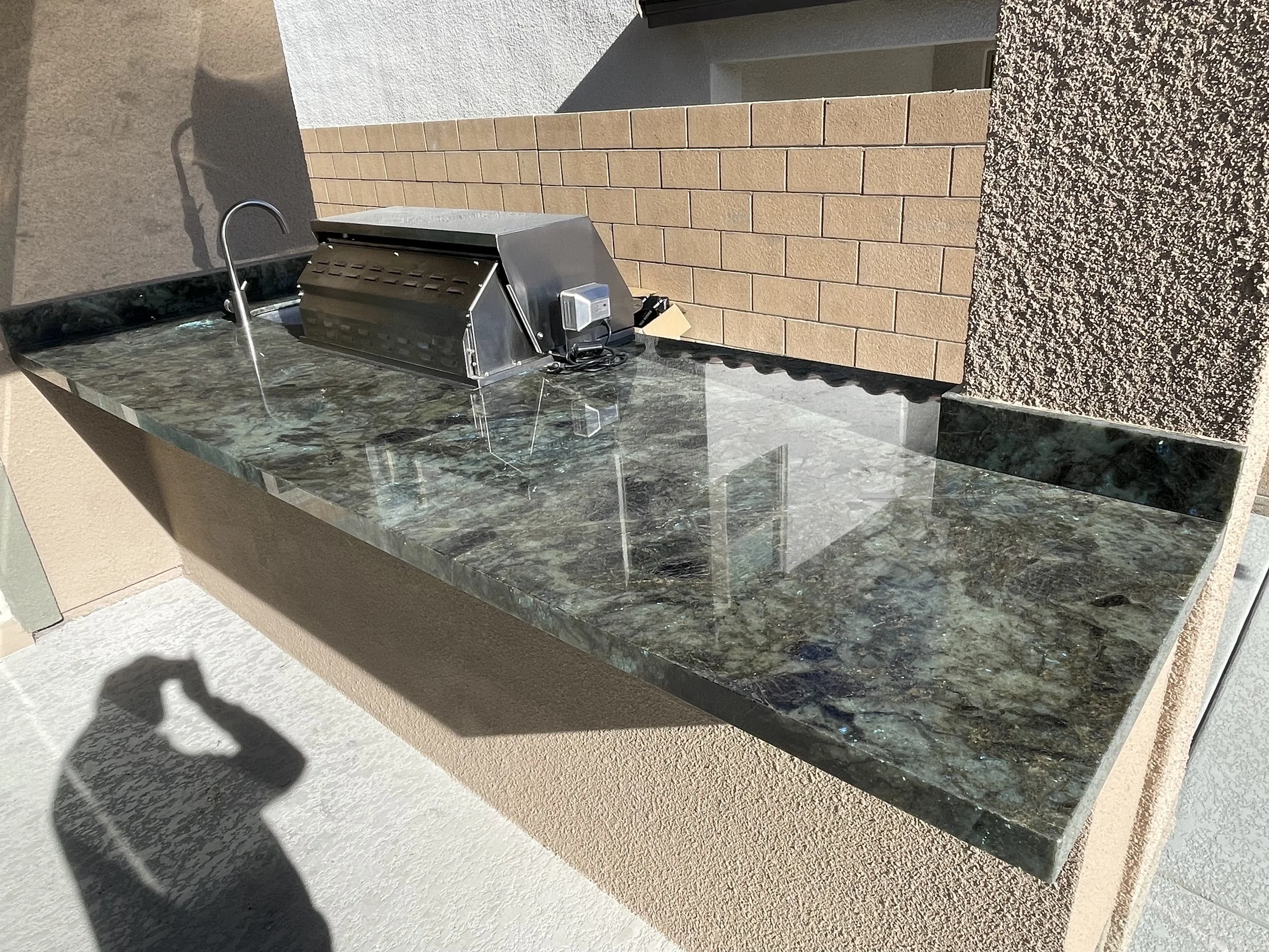 Outdoor kitchen with marble countertop, grill, and backsplash tiles