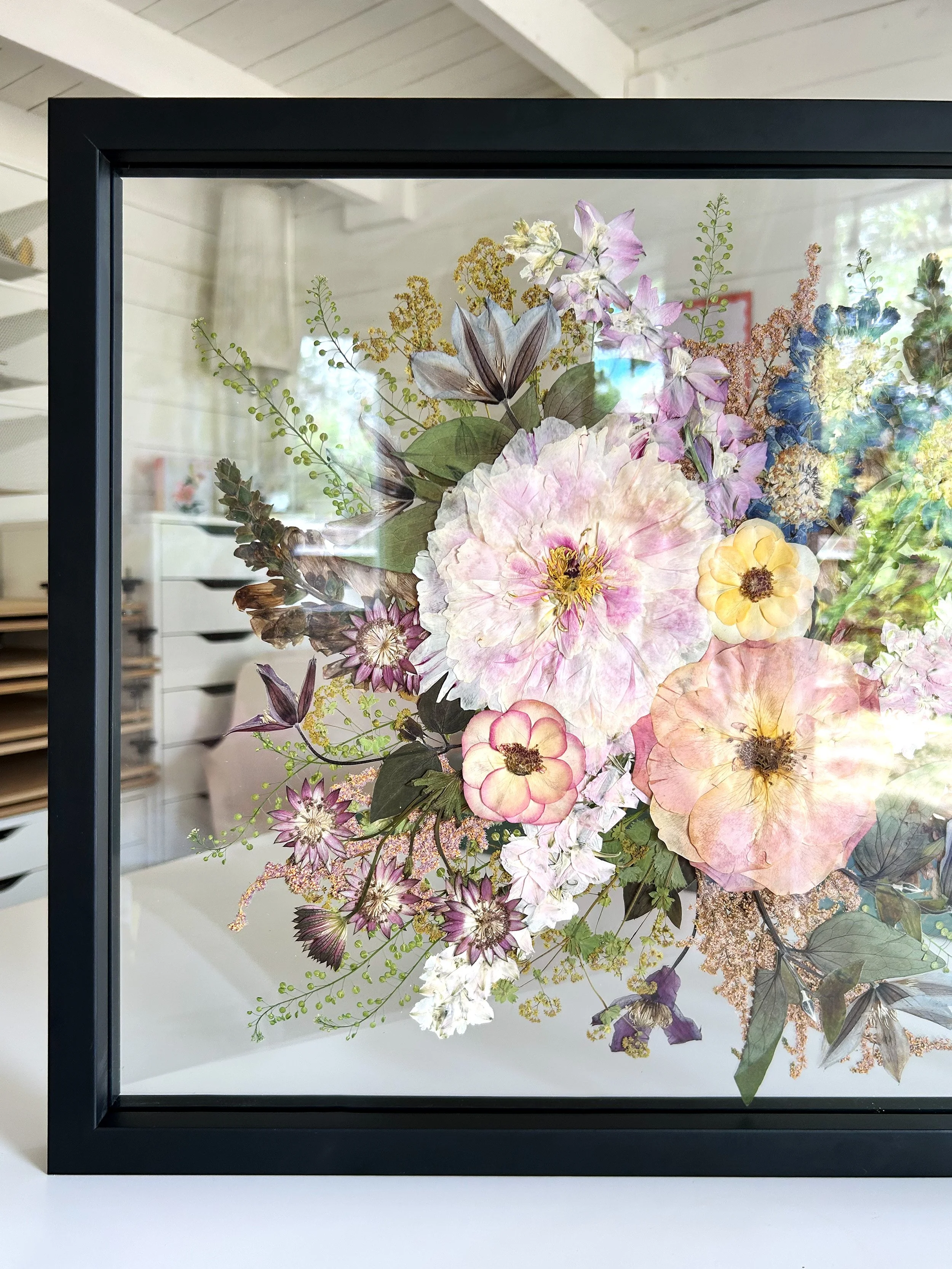 Framed artwork of a bouquet of multicolored flowers in a glass case