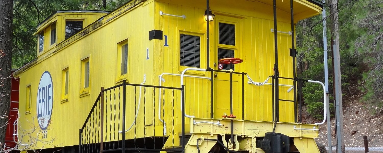 Entrance with stairs to a yellow caboose #1 with the word "Erie" painted on the side