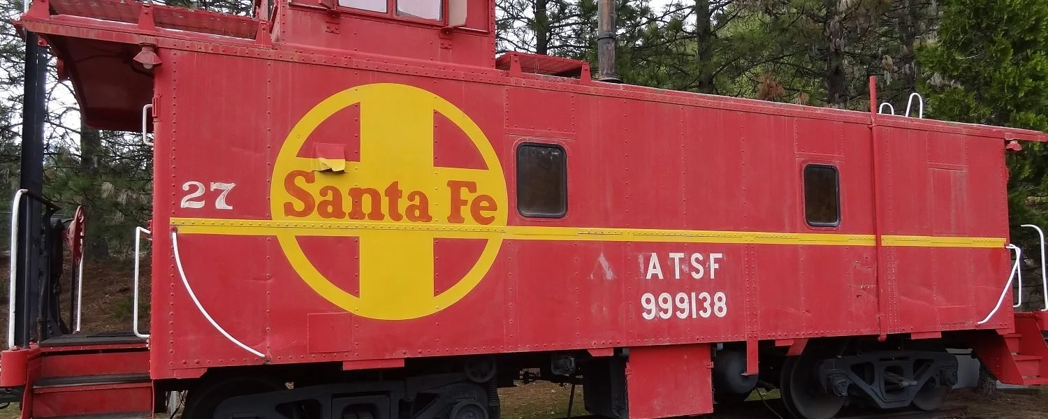 Santa Fe caboose #27 with the woods in the background.