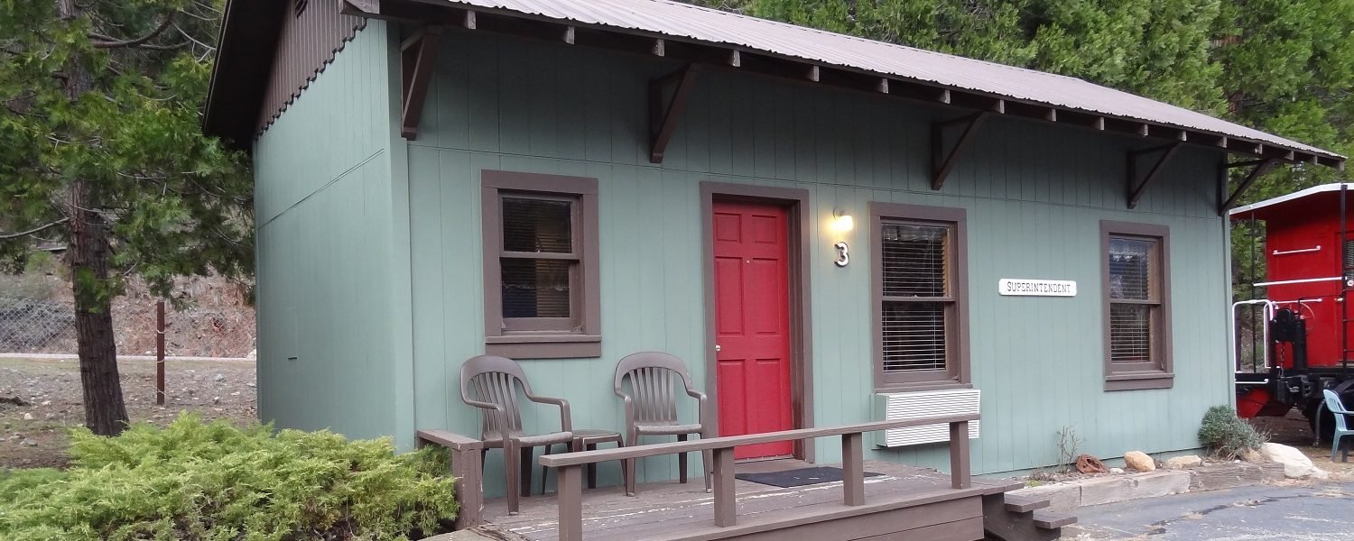 Small cozy cabin with two chairs on a front porch with stairs.