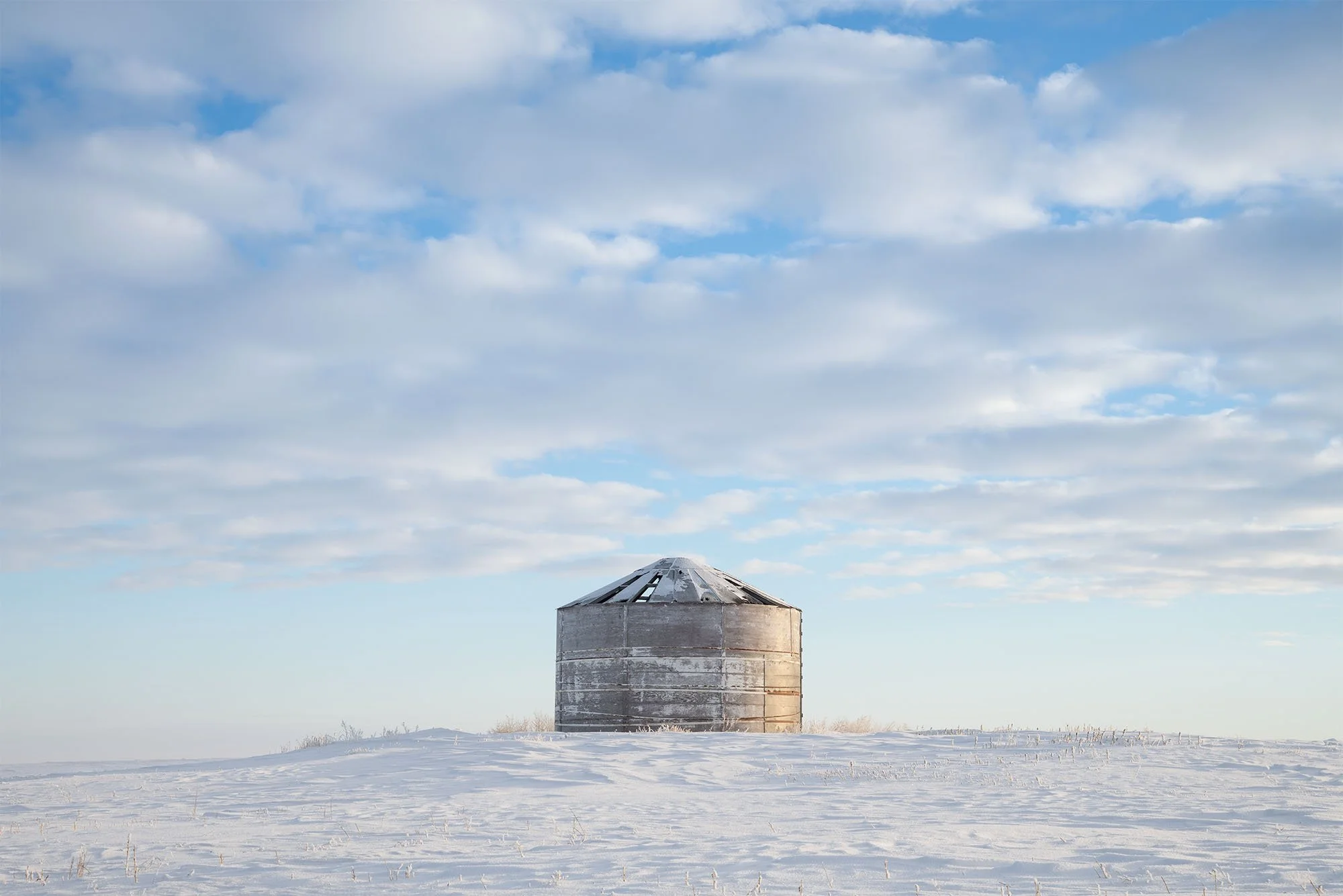 Round grain bin in a snow covered field
