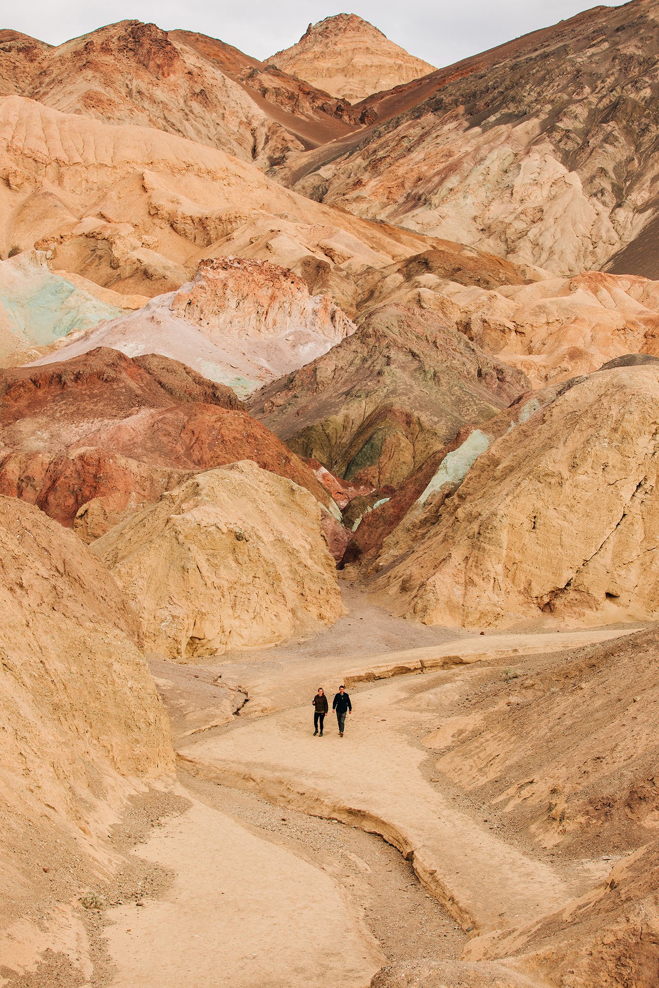 A couple walks through the colorful hills of Death Valley National Park. 