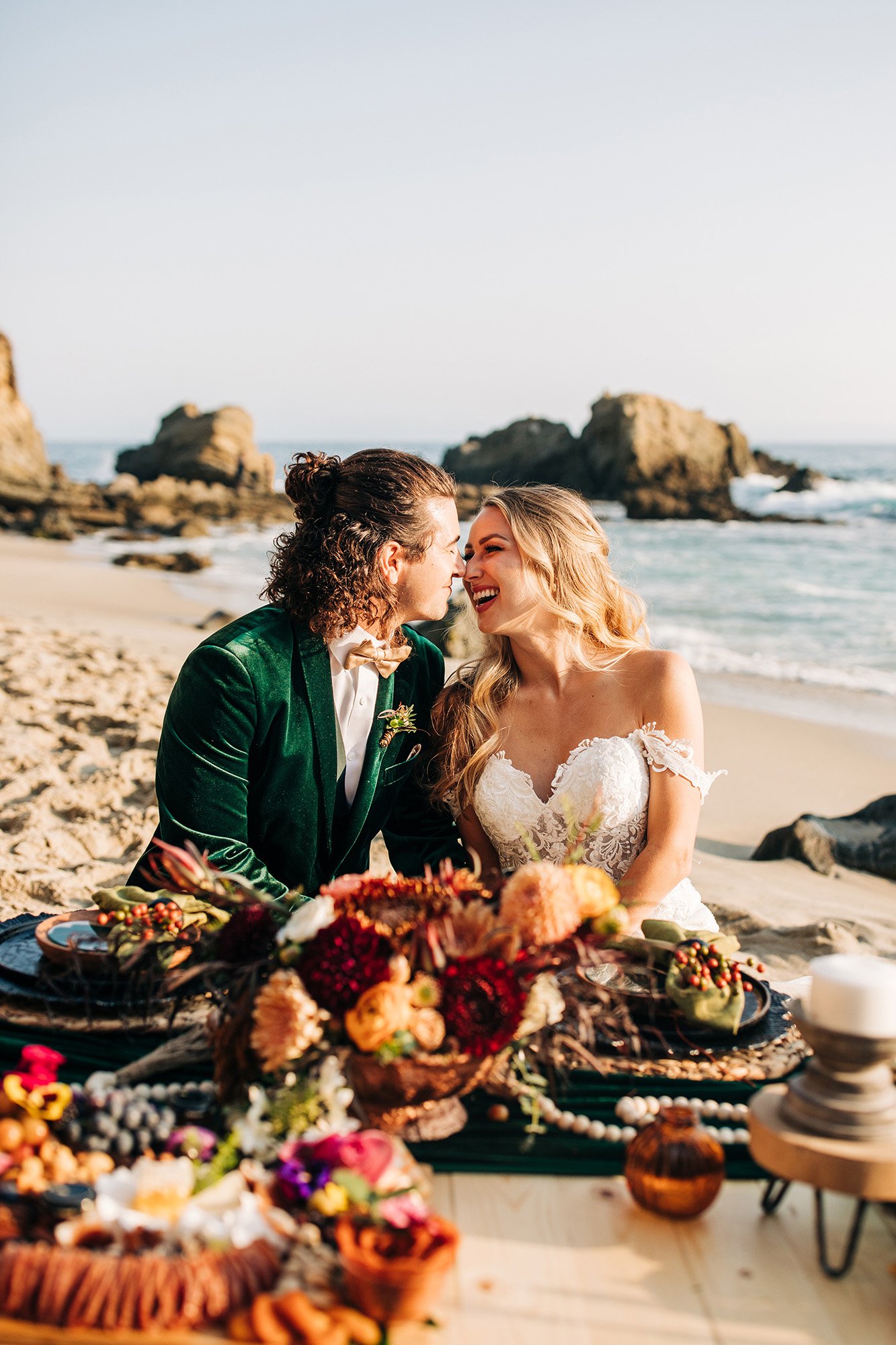 A couple laughs together at their picnic beach wedding.