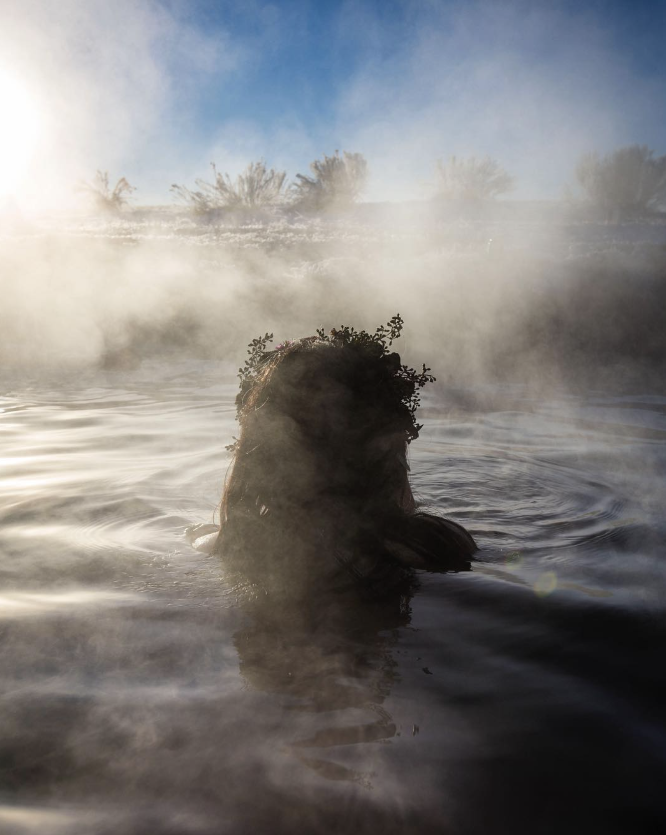 A silhouette of a woman in a hot springs at sunrise.