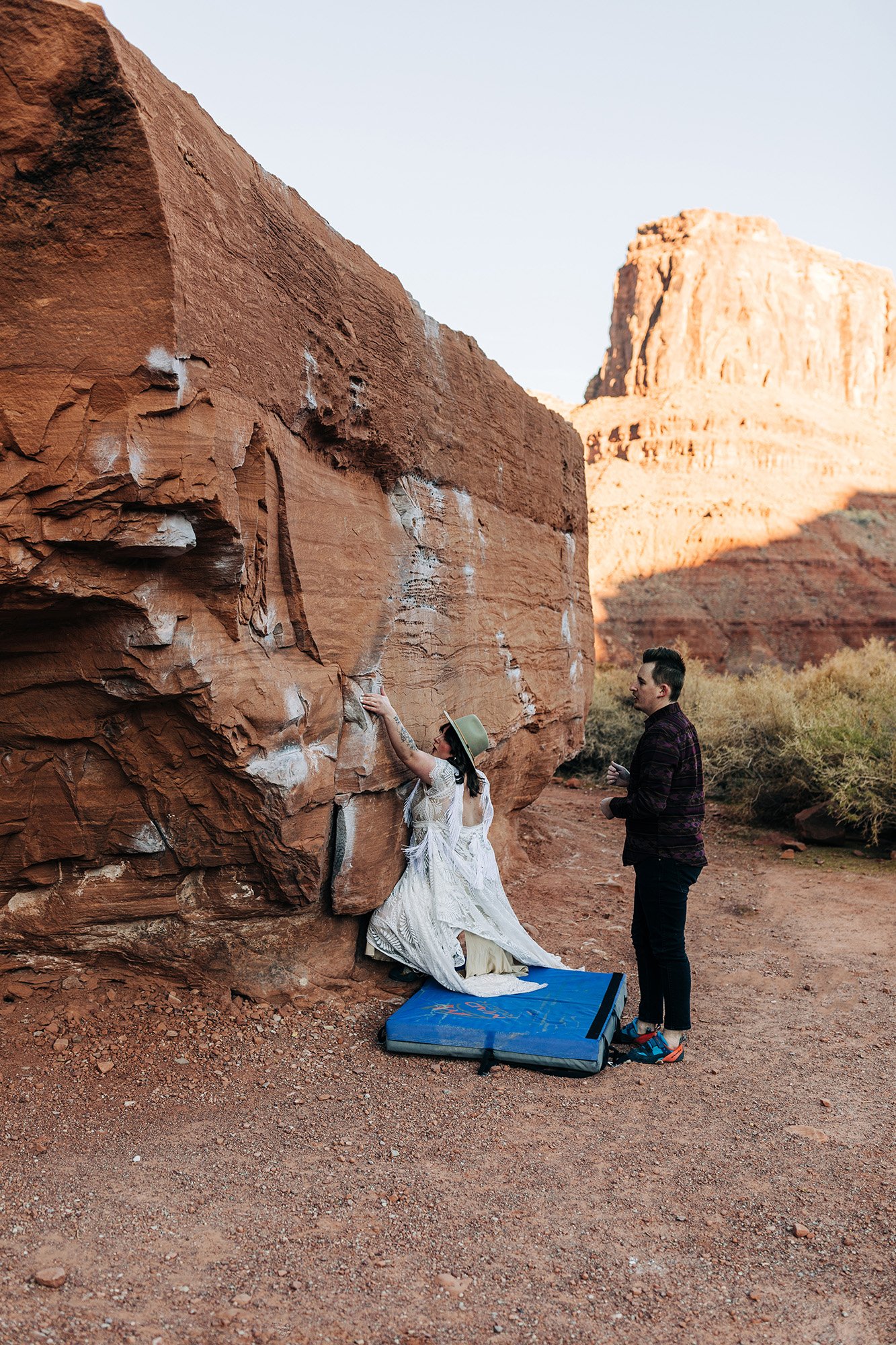 A couple climbs together on their wedding day in Moab.