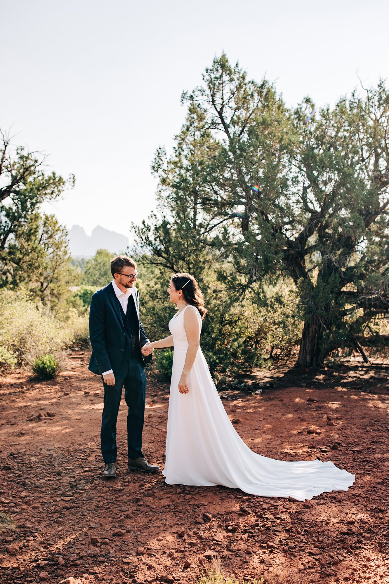 Stephanie and Matthew share a first look moment amongst trees and red rocks. 